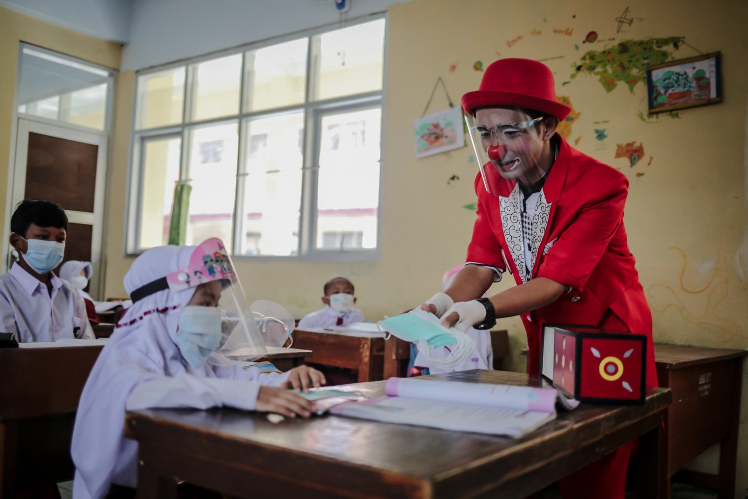 Seniman Aku Badut Indonesia (ABI) memasangkan masker kepada siswa di SDN 03 Citayam, Kabupaten Bogor, Jawa Barat, Senin (6/9/2021). Kegiatan aksi kampanye tersebut tentang protokol kesehatan serta membagikan masker kepada anak-anak sekolah yang menggelar Pembelajaran Tatap Muka (PTM)
