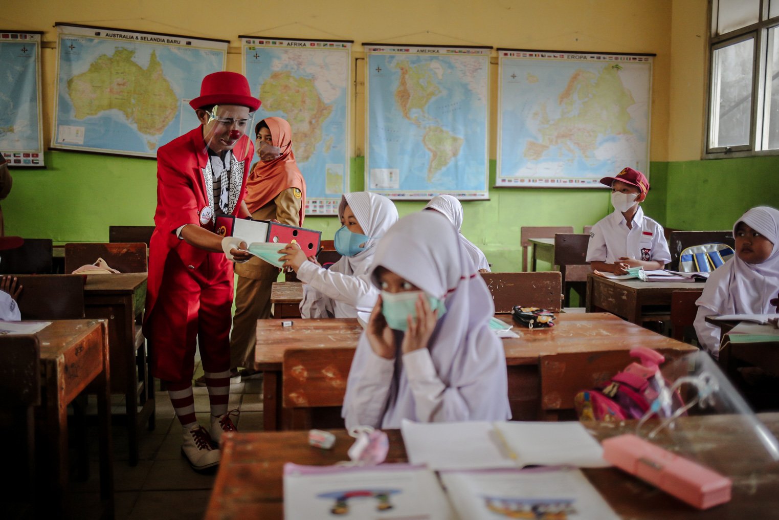 Seniman Aku Badut Indonesia (ABI) membagikan masker kepada siswa di SDN 03 Citayam, Kabupaten Bogor, Jawa Barat, Senin (6/9/2021). Kegiatan aksi kampanye tersebut tentang protokol kesehatan serta membagikan masker kepada anak-anak sekolah yang menggelar Pembelajaran Tatap Muka (PTM)