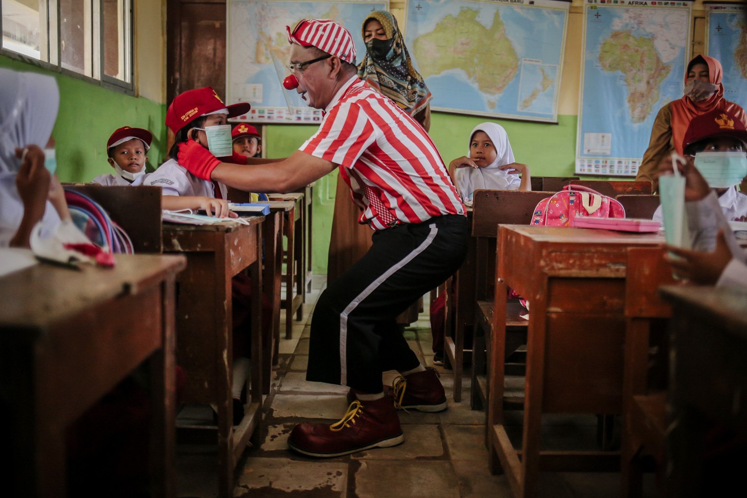 Seniman Aku Badut Indonesia (ABI) memasangkan masker kepada siswa di SDN 03 Citayam, Kabupaten Bogor, Jawa Barat, Senin (6/9/2021). Kegiatan aksi kampanye tersebut tentang protokol kesehatan serta membagikan masker kepada anak-anak sekolah yang menggelar Pembelajaran Tatap Muka (PTM)