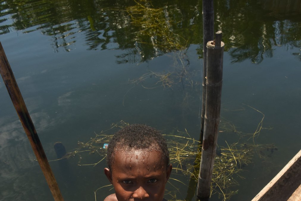 Seorang anak berdiri diatas perahu memegang tombak untuk mecari ikan di Kampung Yoboi, Distrik Sentani, Jayapura
