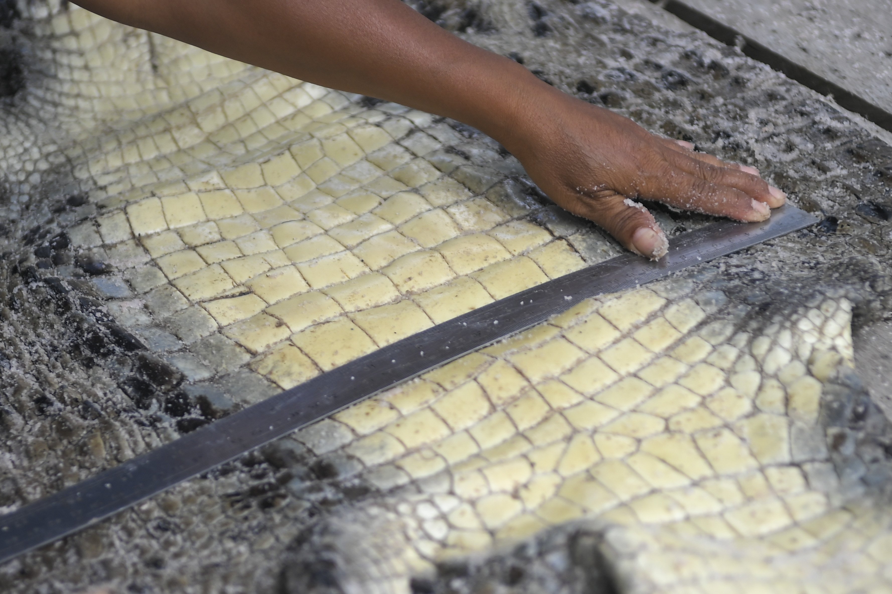 Pekerja mengukur kulit buaya menggunakan penggaris besi untuk dibuat pola kerajinan tangan di Merauke, Papua.