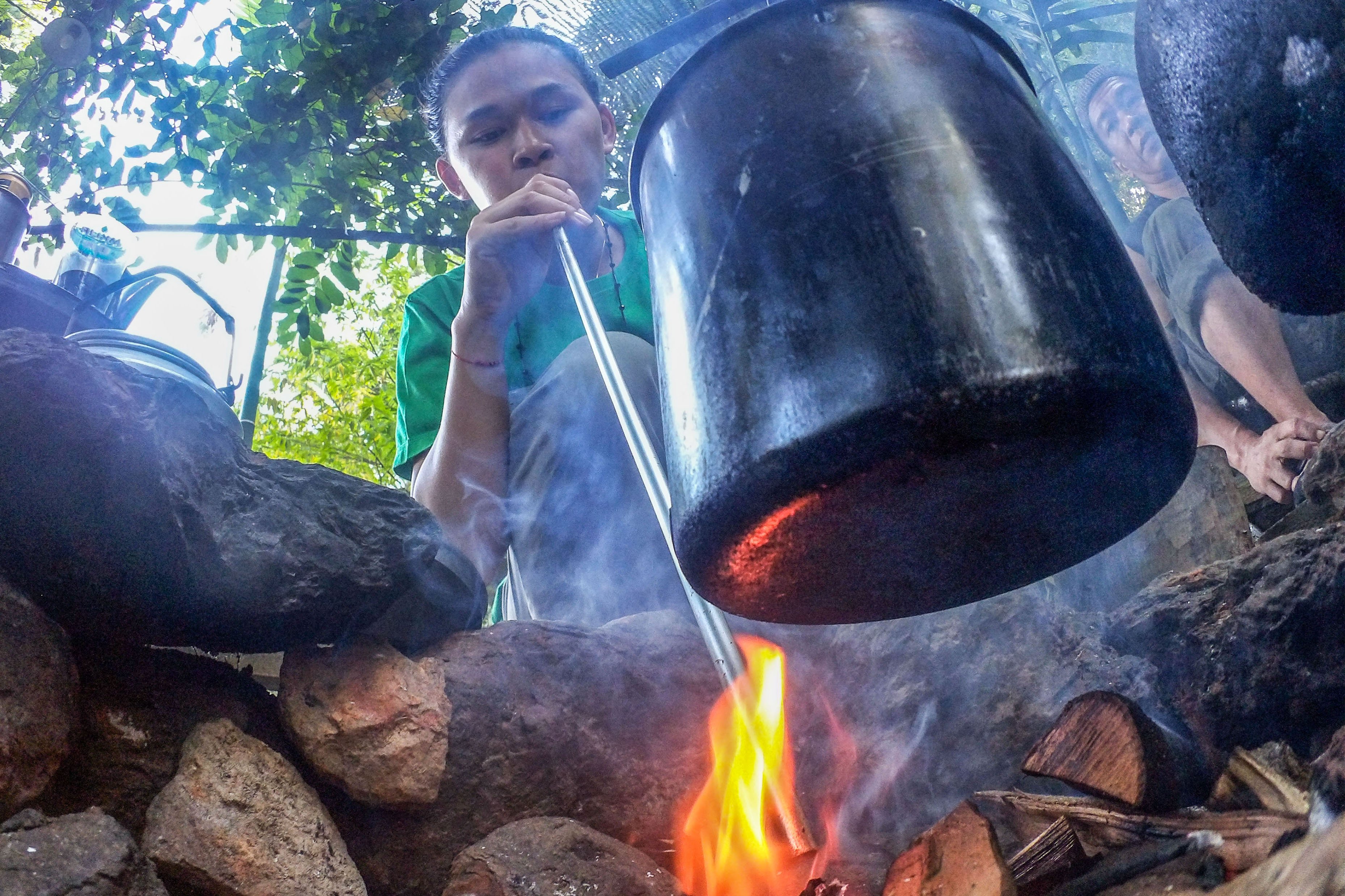 Seorang pekerja meniup api menggunakan pipa besi saat merebus bahan baku herbal di Balikpapan, Kalimantan Timur.