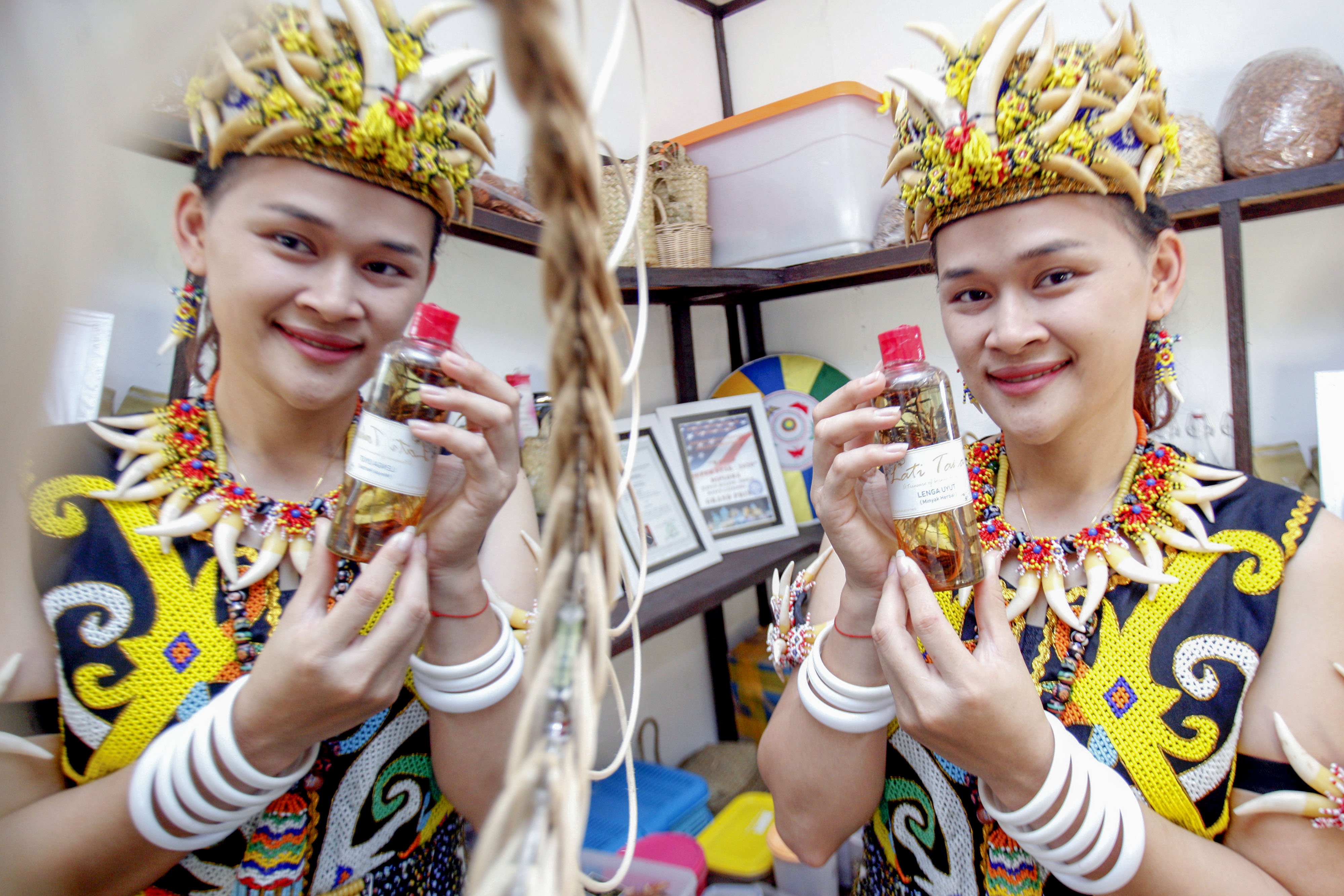 Pekerja mengenakan baju adat Suku Dayak menunjukkan produk obat herbal tradisonal Lati Taka yang siap dijual di Balikpapan,Kalimantan Timur.