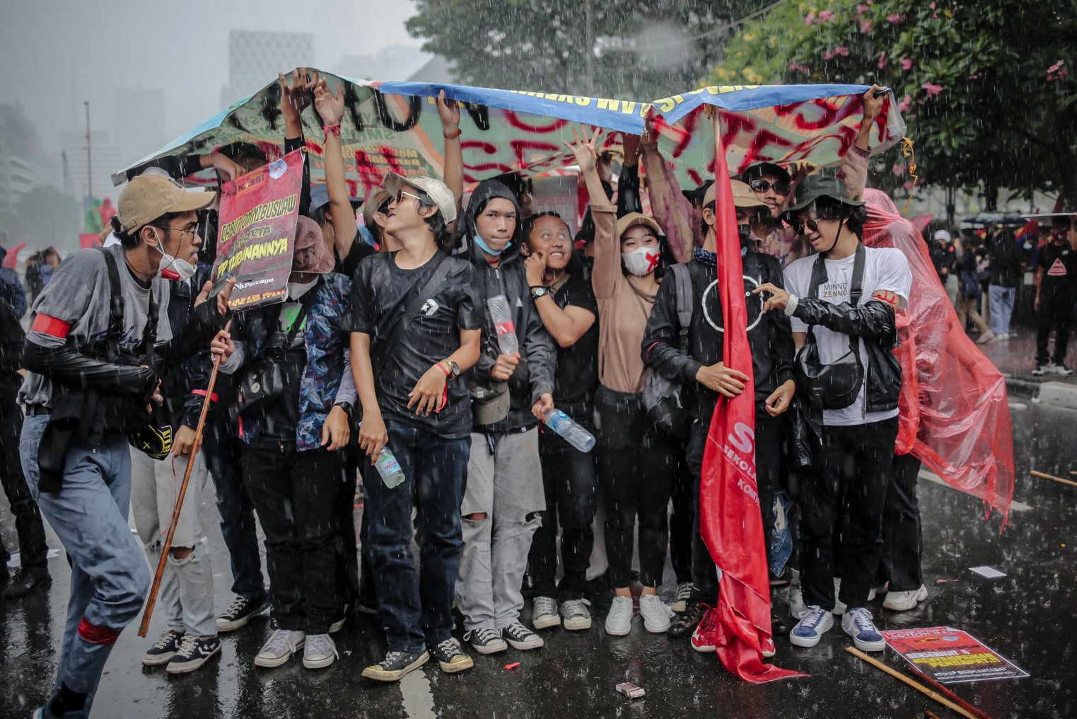 Masa aksi berteduh menggunakan terpal saat melakukan unjuk rasa di Wilayah Patung Kuda, Jakarta, Kamis (28/10/2021). Dalam aksinya demonstran yang tergabung dari mahasiswa dan buruh meyuarakan 13 tuntutan diantaranya Cabut Omnibus Law dan seluruh PP turunannya.