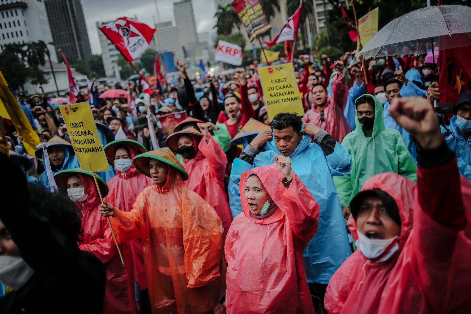 Masa aksi menggunakan jas hujan mengepalkan tangan kiri saat melakukan unjuk rasa di Wilayah Patung Kuda, Jakarta, Kamis (28/10/2021). Dalam aksinya demonstran yang tergabung dari mahasiswa dan buruh meyuarakan 13 tuntutan diantaranya Cabut Omnibus Law dan seluruh PP turunannya.