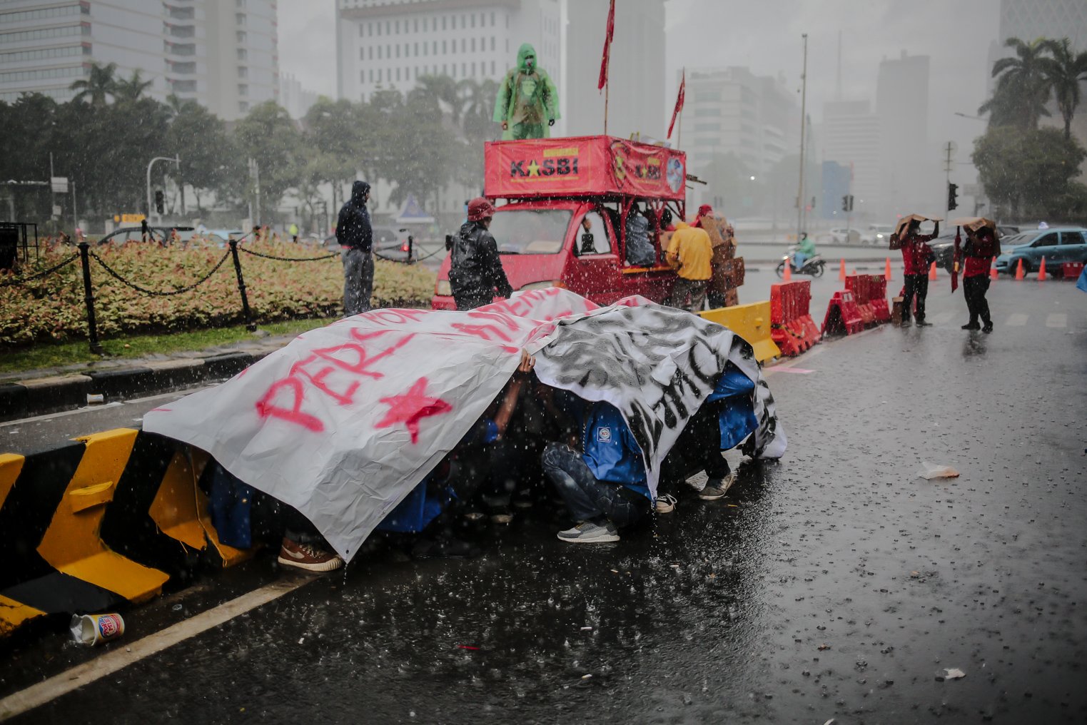 Masa aksi berteduh menggunakan terpal saat melakukan unjuk rasa dalam memperingati hari sumpah pemuda di Wilayah Patung Kuda, Jakarta, Kamis (28/10/2021). Dalam aksinya demonstran yang tergabung dari mahasiswa dan buruh meyuarakan 13 tuntutan diantaranya Cabut Omnibus Law dan seluruh PP turunannya.