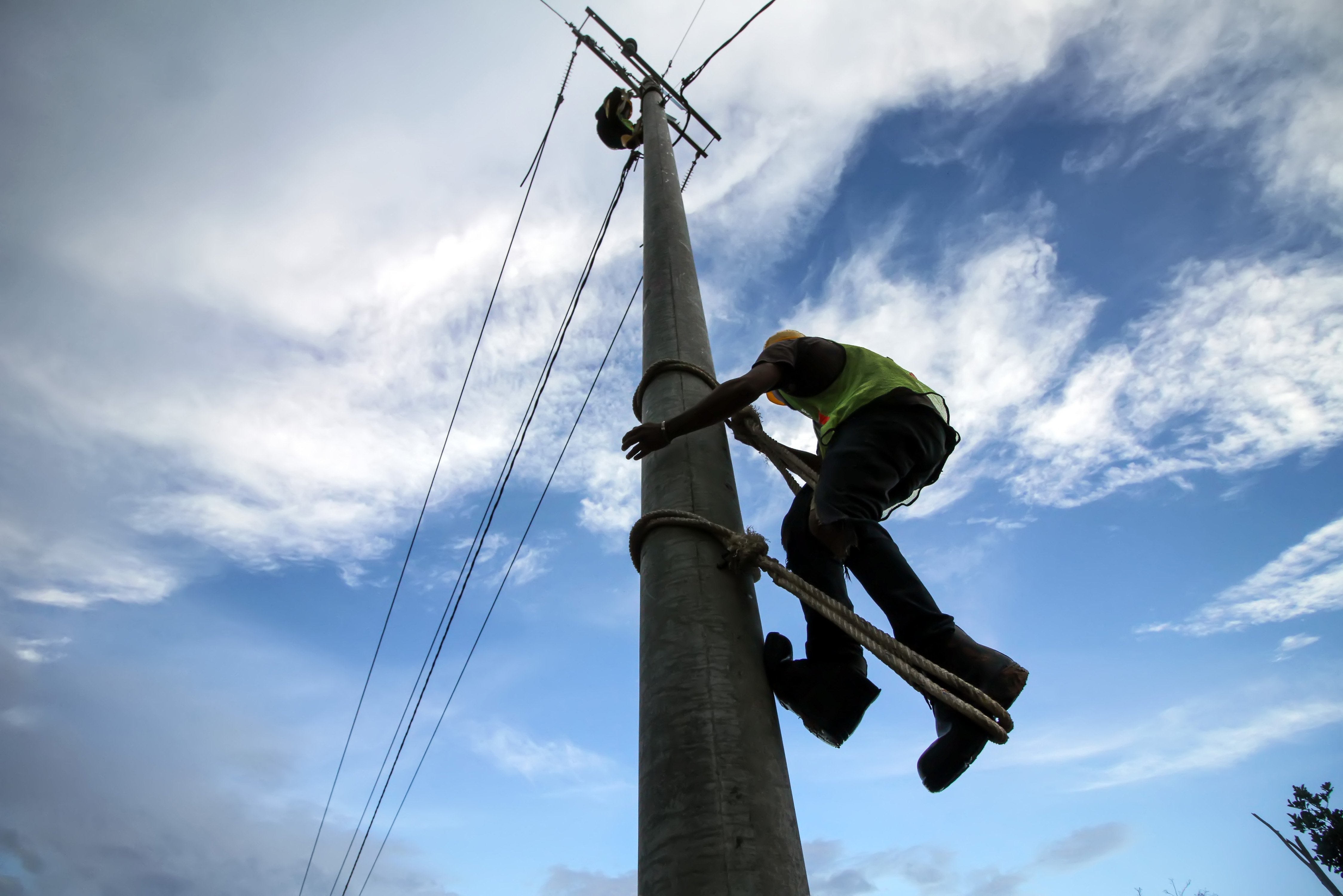 Pekerja memanjat tiang listrik saat pengerjaan pemasangan jaringan listrik program listrik masuk wilayah desa tertinggal di Dusun Jabal Antara, Aceh Utara.