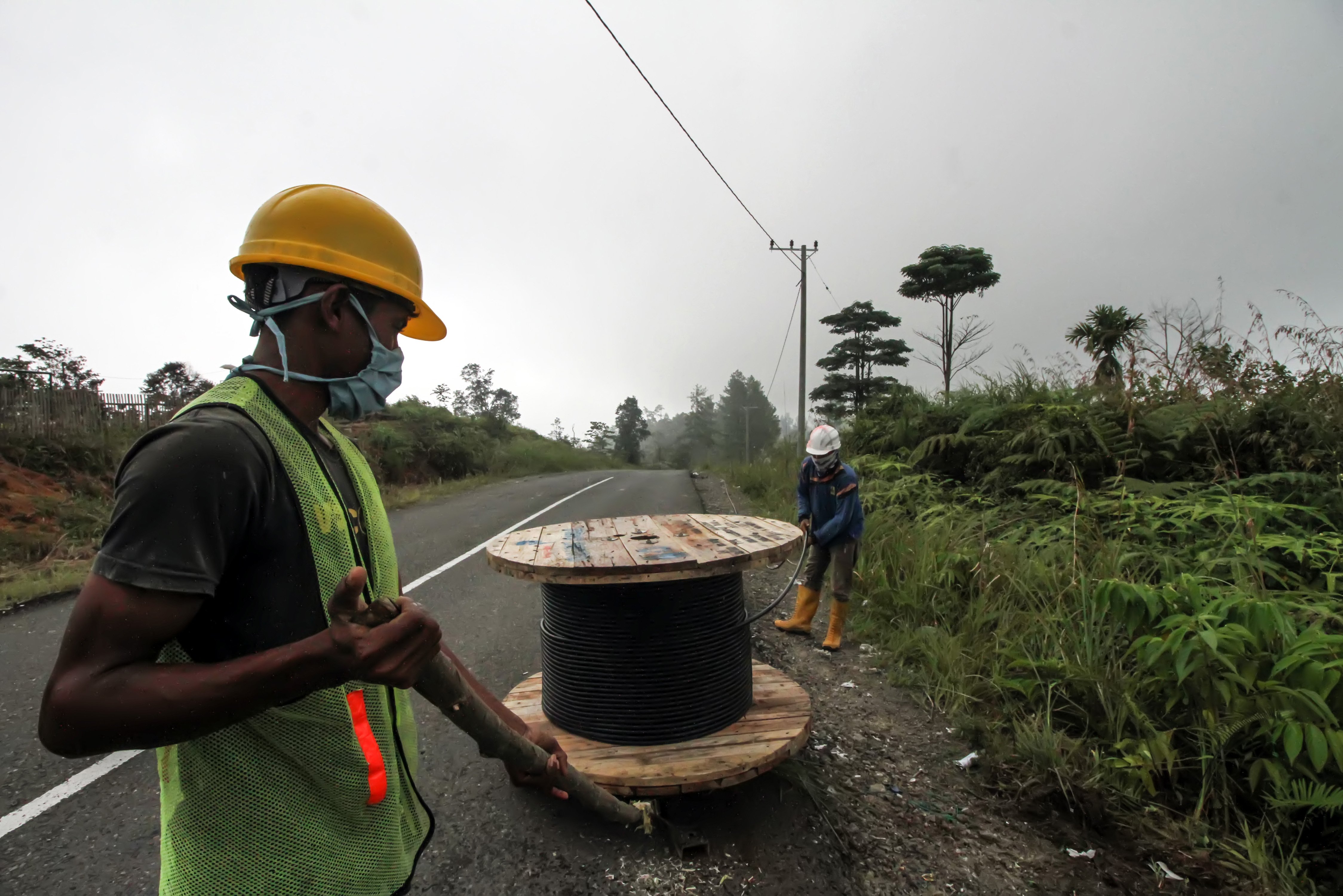 Pekerja menarik kabel listrik saat pengerjaan pemasangan jaringan listrik program listrik masuk wilayah desa tertinggal di Dusun Jabal Antara, Aceh Utara.
