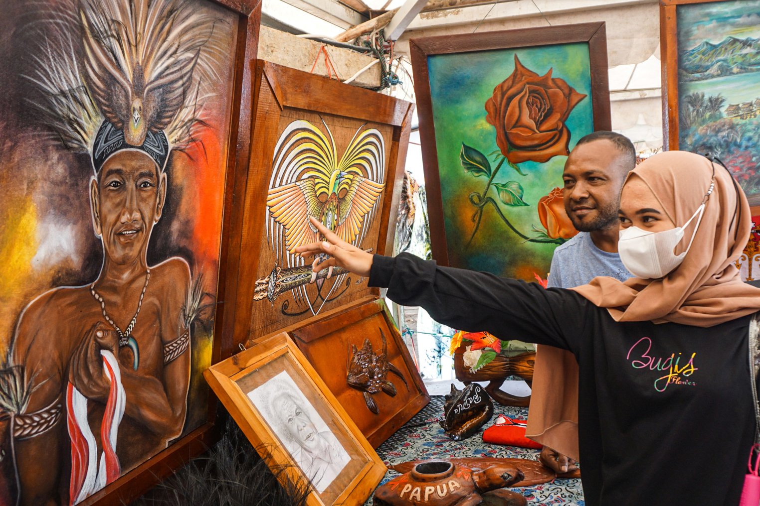Pengunjung memilih lukisan lukisan kulit kayu yang dibelinya di Stan Sanggar Seni Yauw Alloz Chrisyen (YAC) Art Work, saat Pameran dan Pagelaran Budaya Nasional di Holtekamp, Jayapura, Papua.