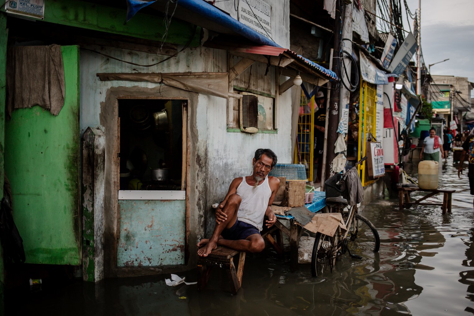 Warga duduk di depan urmahnya yang terendam banjir rob air laut di Muara Angke, Jakarta Utara, Selasa (9/11/2021). Laporan Fitch Solutions Country Risk & Industry Research memprediksi wilayah utara Jakarta dapat tenggelam secara menyeluruh pada tahun 2050 jika tidak ada intervensi lebih lanjut dari pemerintah.