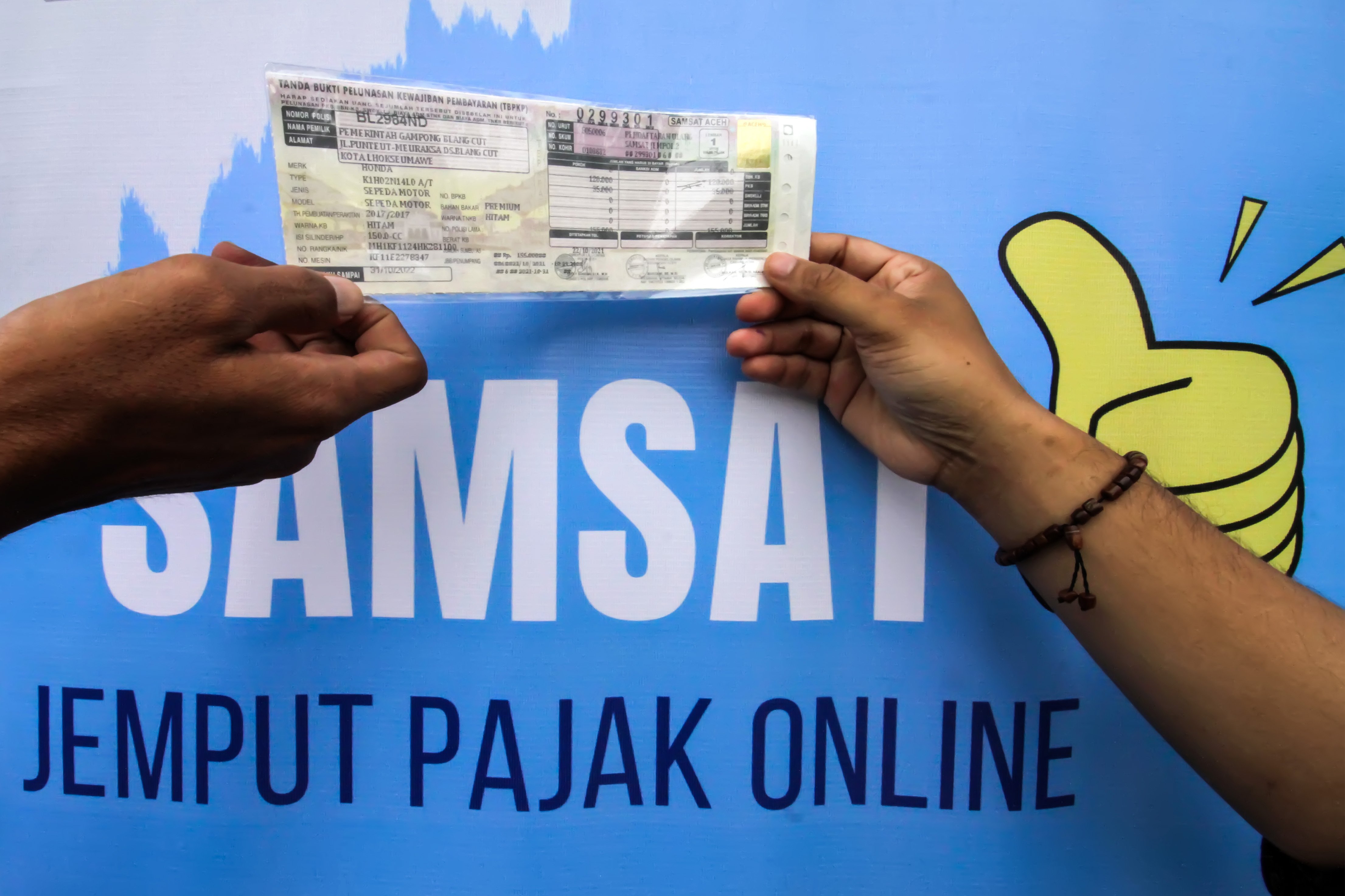 Petugas menyerahkan tanda bukti pelunasan kewajiban pajak kendaraan secara daring melalui sepeda motor Sijempol di Kecamatan Blang Mangat, Lhoksumawe, Aceh.