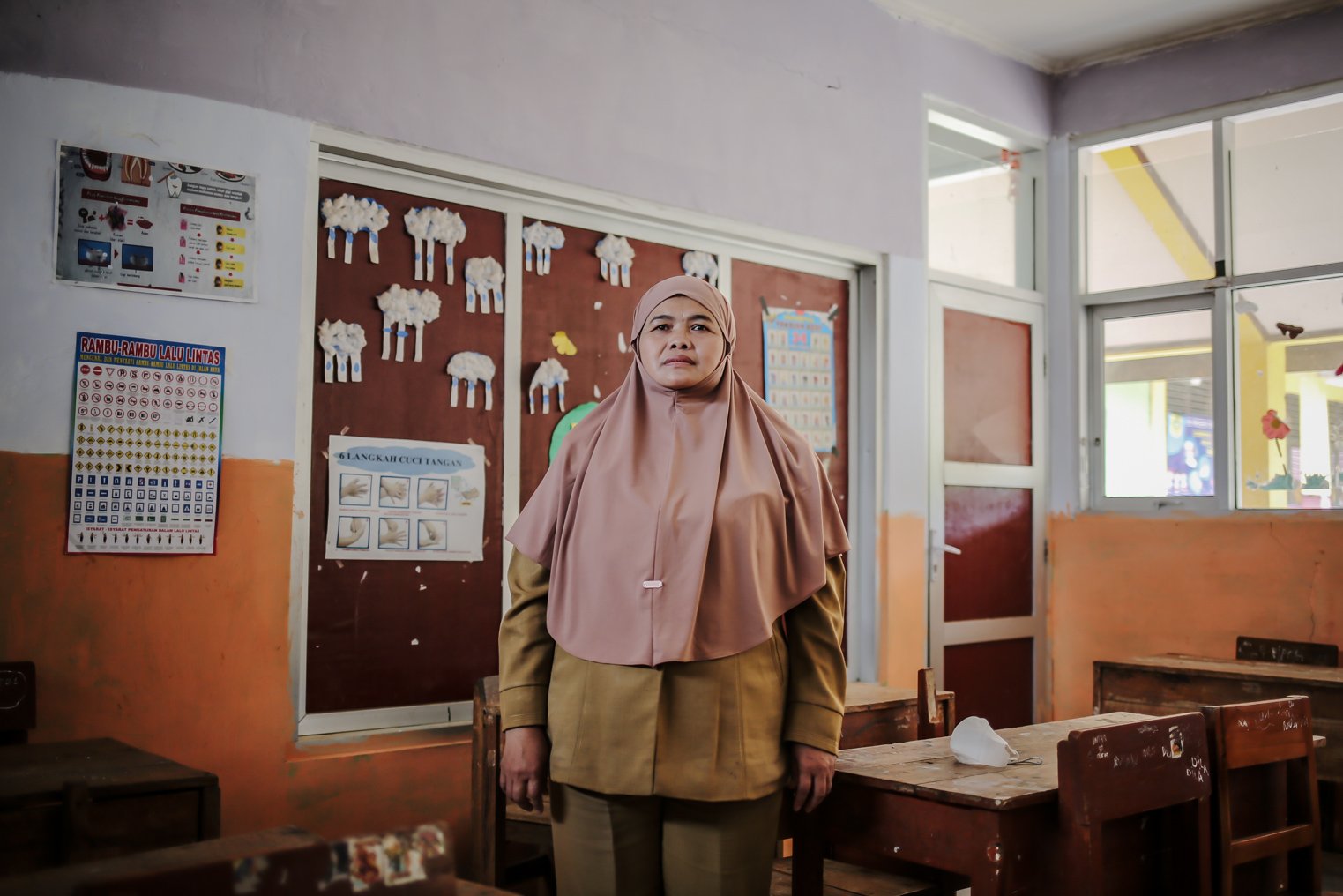 Ani Fatawati berdiri di dalam ruangan kelas di SDN Cikoneng, Desa Tugu Utara, Cisarua, Bogor, Jawa Barat, Rabu (24/11/2021). Sudah hampir 17 tahun Ani menjadi guru honorer. Penyakit asma dalam tubuhnya bukan halangan ia berhenti mengajar meski terkadang harus berjalan kaki dengan jarak yang jauh.