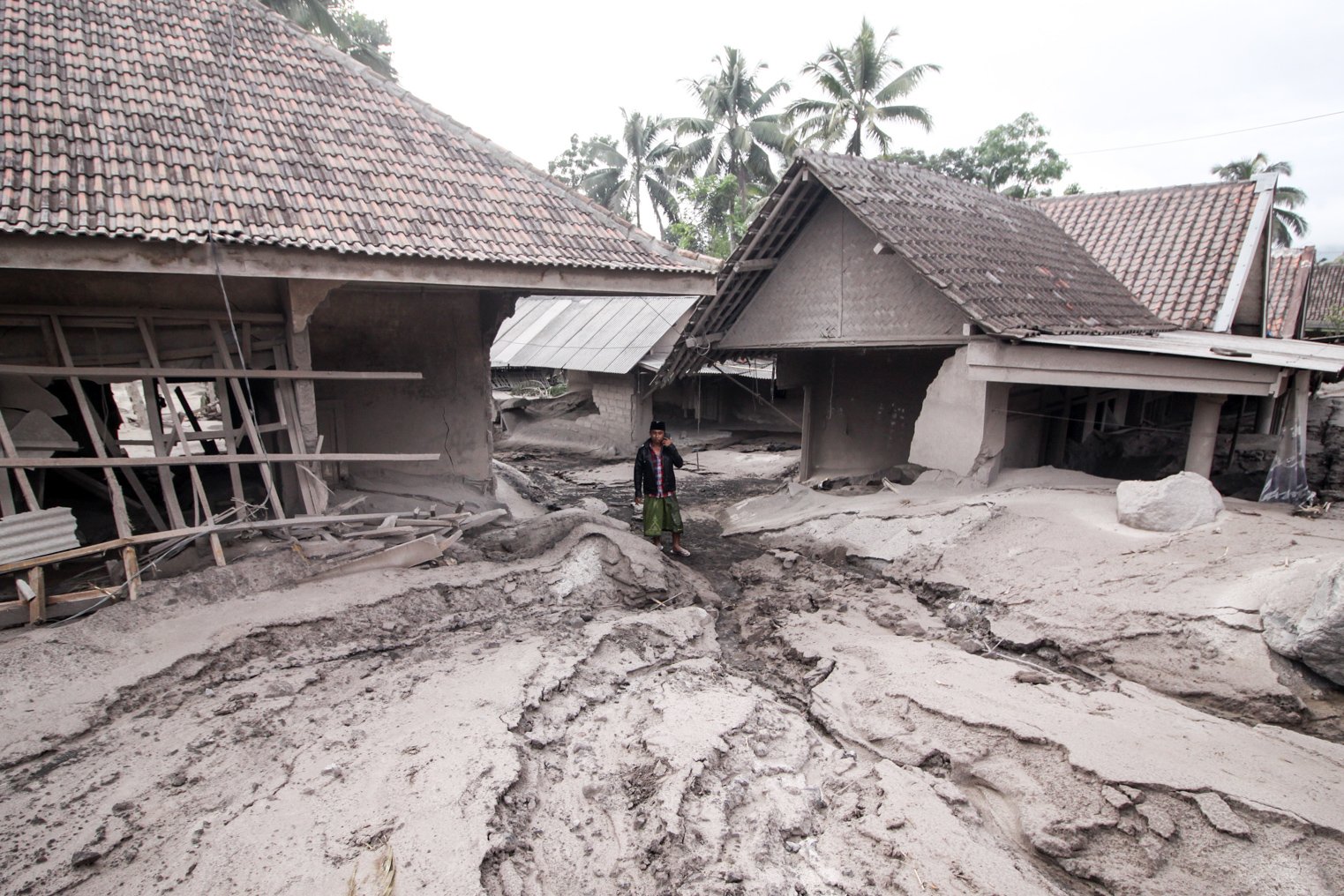Warga melintas di rumah yang rusak akibat abu vulkanik letusan Gunung Semeru di Desa Sumber Wuluh, Lumajang, Jawa Timur, Minggu (5/12/2021). Akibat letusan Gunung Semeru tersebut sedikitnya puluhan rumah rusak. ANTARA FOTO/Umarul Faruq/pras.