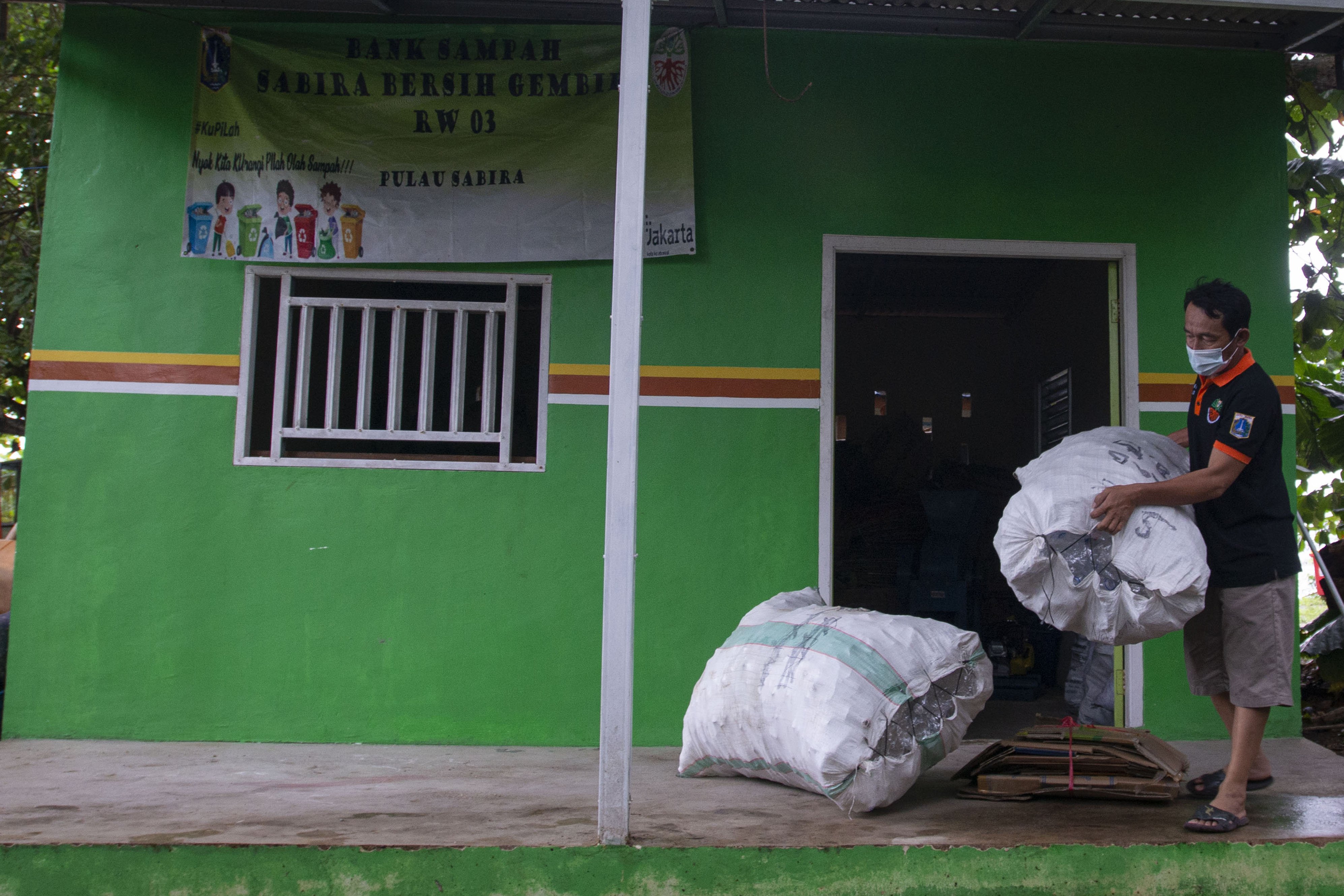 Petugas Bank Sampah Sabira Bersih Gembira menata karung beirisi limbah plastik yang dikumpulkan warga di Pulau Sabira, Kepulauan Seribu, Provinsi DKI Jakarta.