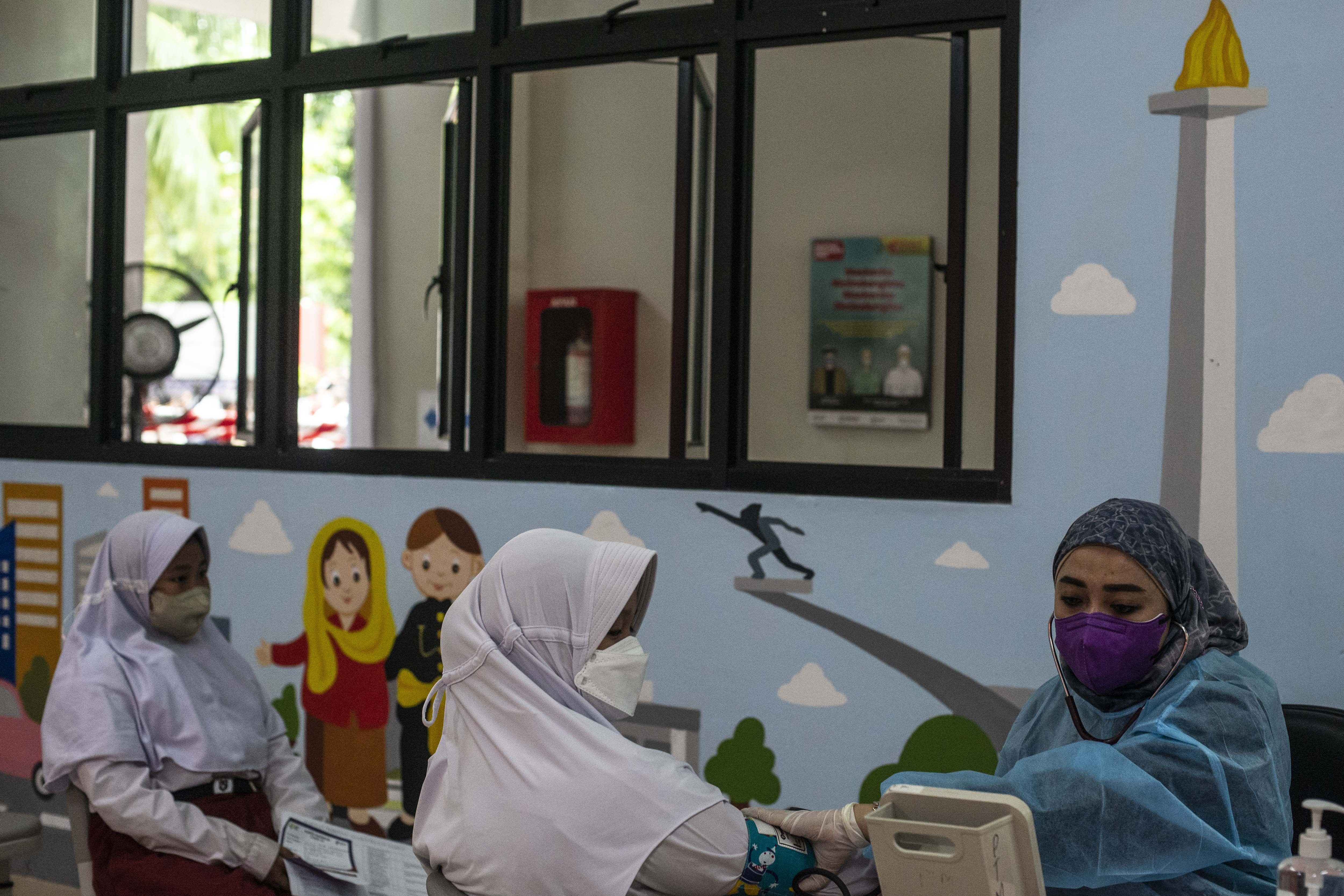 Tenaga kesehatan (kanan) melakukan pemeriksaan kesehatan kepada pelajar sebelum menerima suntikkan vaksin COVID-19 di SDN Cempaka Putih Timur 03, Jakarta, Selasa (14/12/2021). Kementerian Kesehatan memulai vaksinasi COVID-19 untuk anak usia 6-11 dengan jumlah sasaran vaksinasi mencapai 26,5 juta di Indonesia. ANTARA FOTO/Aprillio Akbar/hp.