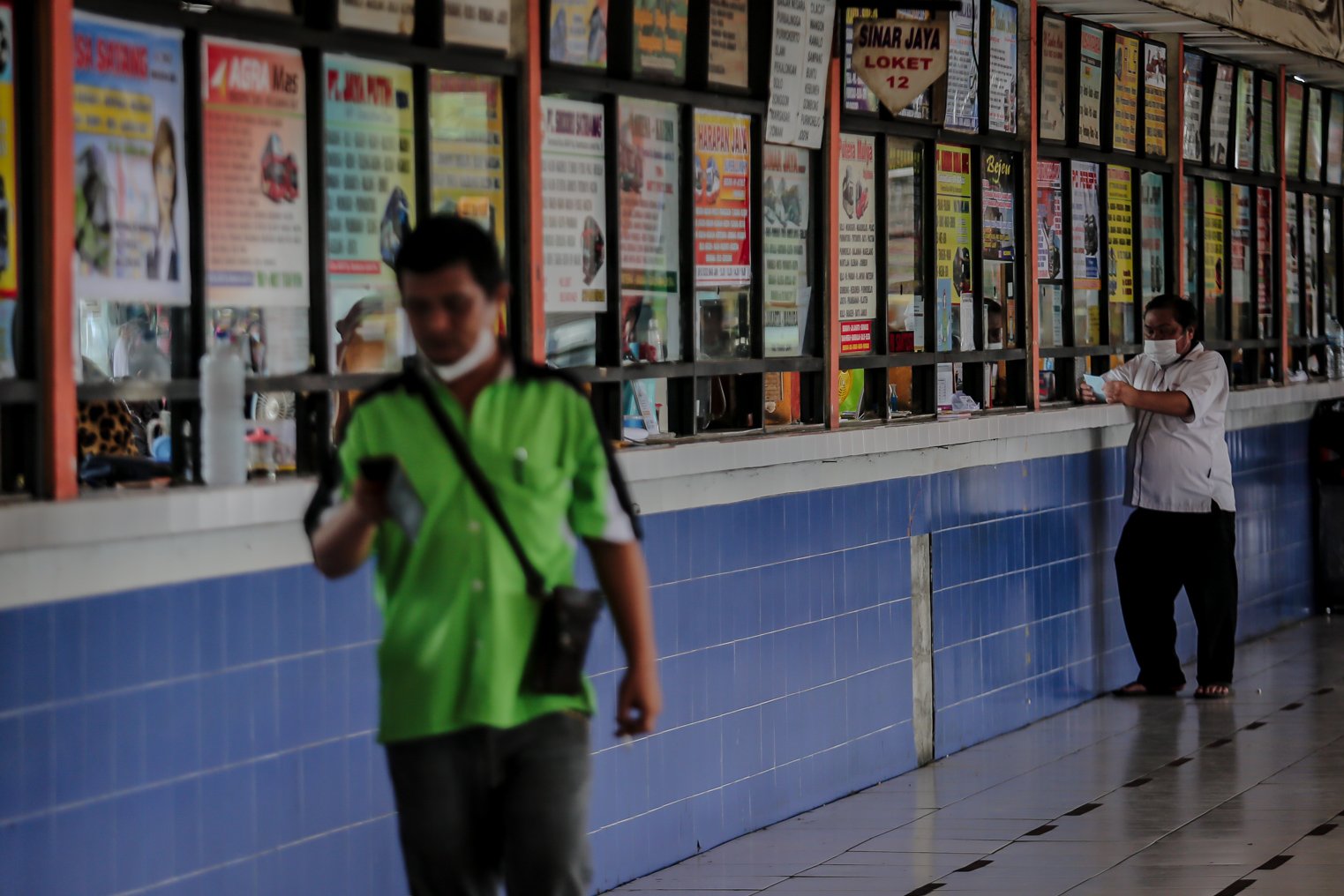 Sejumlah calon penumpang berdiri di depan loket sebelum keberangkatan di Terminal Kampung Rambutan, Jakarta, Selasa (21/12/2021). Kepala Terminal Kampung Rambutan Yulza Ramadhoni mengatakan, jumlah penumpang bus alami kenaikan hingga 10 persen pada menjelang Natal 2021 dan Tahun Baru 2022.