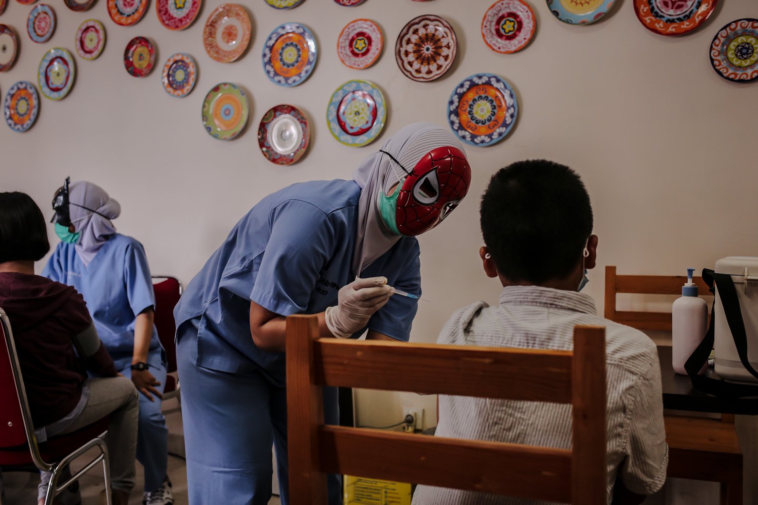 Petugas Kesehatan menegakan topeng super hero saat menyuntikkan vaksin covid-19 untuk anak-anak usia 6-11 tahun di Rumah Sakit Ibu dan Anak (RSIA) Tambak, Jakarta, Rabu (22/12/2021). Upaya tersebut dilakukan pihak rumah sakit untuk menarik minat anak-anak mengikuti vaksinasi Covid-19.