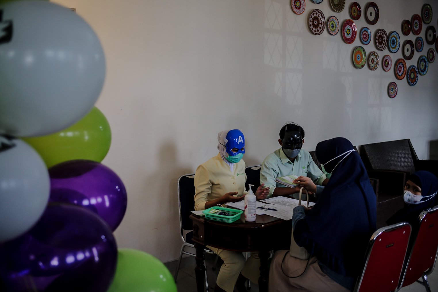 Petugas Kesehatan menegakan topeng super hero melakukan registrasi sebelum menyuntikkan vaksin covid-19 untuk anak-anak usia 6-11 tahun di Rumah Sakit Ibu dan Anak (RSIA) Tambak, Jakarta, Rabu (22/12/2021). Upaya tersebut dilakukan pihak rumah sakit untuk menarik minat anak-anak mengikuti vaksinasi Covid-19.