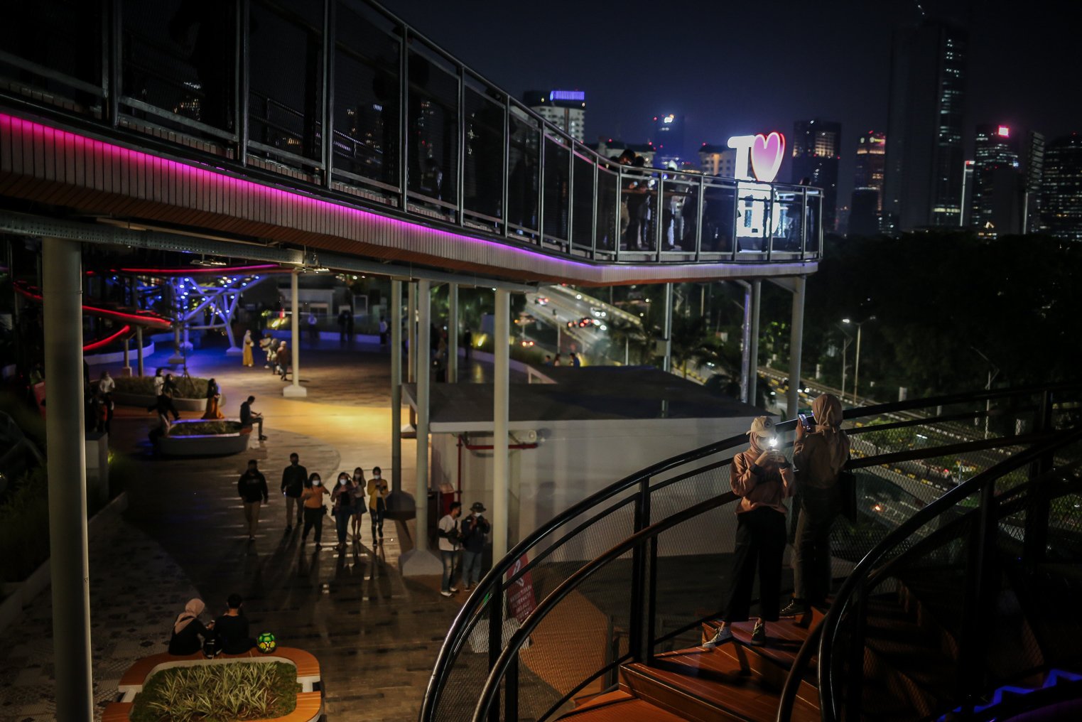 Pengunjung berswafoto dengan latar belakang lanskap perkotaan di Skywalk Senayan Park, Jakarta, Jumat (30/12/2021). Kawasan tersebut menjadi salah satu objek wisata ibu kota yang ramai dikunjungi oleh warga dengan menyajikan pemandangan lanskap perkotaan.