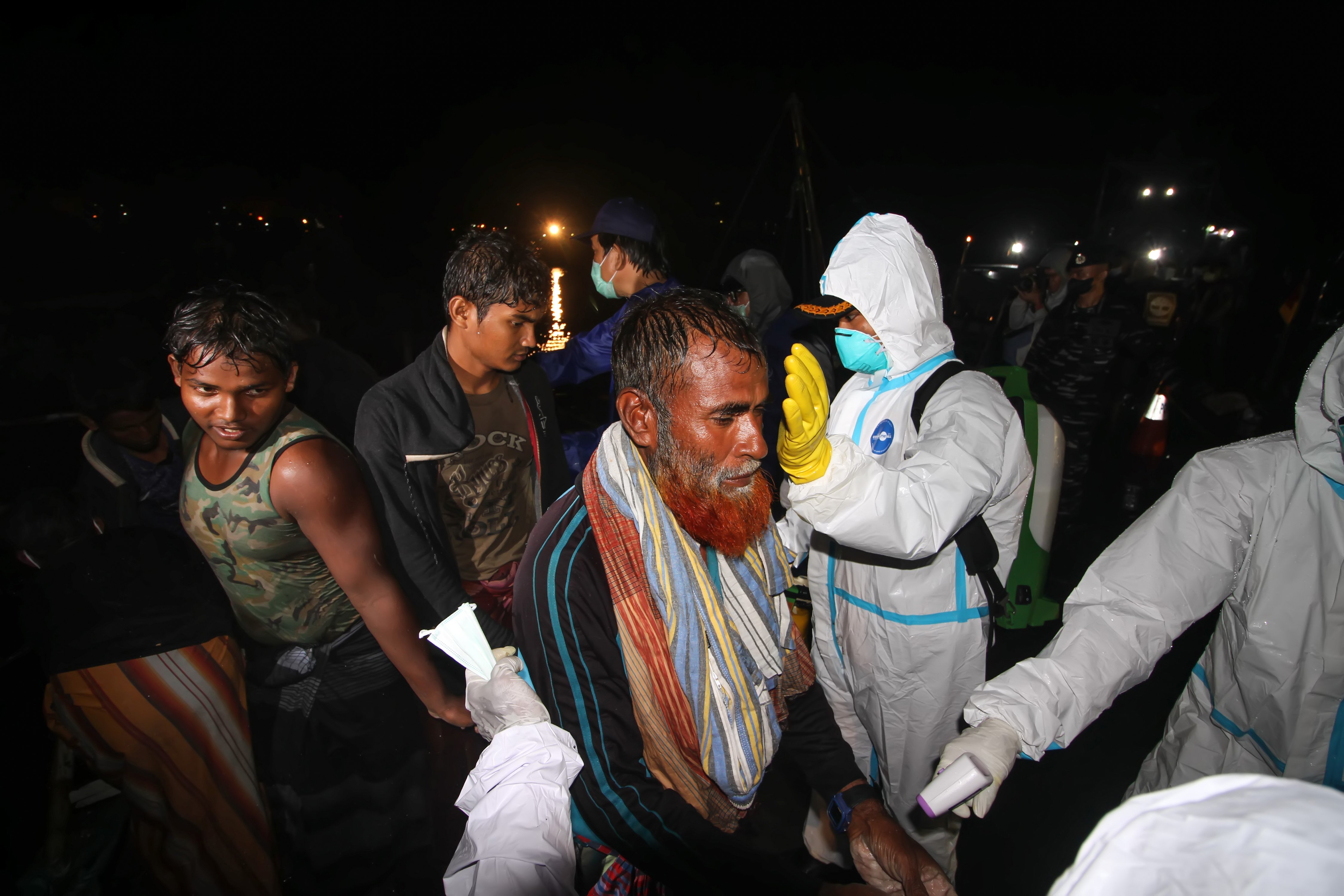Petugas memeriksa suhu tubuh para pengungsi etnis Rohingya saat proses evakuasi oleh TNI AL di Pelabuhan ASEAN, Krueng Geukuh, Aceh Utara, Aceh, Jumat (31/12/2021). Pemerintah Indonesia melalui Satgas Penanganan Pengungsi Luar Negeri (PPLN) mempertimbangkan keadaan darurat dan sisi kemanusiaan sehingga memutuskan untuk menyelamatkan 120 orang etnis Rohingya terdiri dari tujuh laki-laki, 62 perempuan dan 51 anak-anak yang terdampar di perairan laut Aceh pada Sabtu (25/12/2021). ANTARA FOTO/Rahmad/nym.
