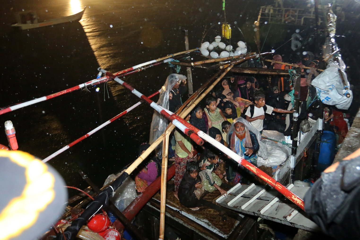 Sejumlah pengungsi etnis Rohingya menunggu di atas perahunya sebelum proses evakuasi di Pelabuhan ASEAN, Krueng Geukuh, Aceh Utara, Aceh, Jumat (31/12/2021). Pemerintah Indonesia melalui Satgas Penanganan Pengungsi Luar Negeri (PPLN) mempertimbangkan keadaan darurat dan sisi kemanusiaan sehingga memutuskan untuk menyelamatkan 120 orang etnis Rohingya terdiri dari tujuh laki-laki, 62 perempuan dan 51 anak-anak yang terdampar di perairan laut Aceh pada Sabtu (25/12/2021). ANTARA FOTO/Syifa Yulinnas/nym.
