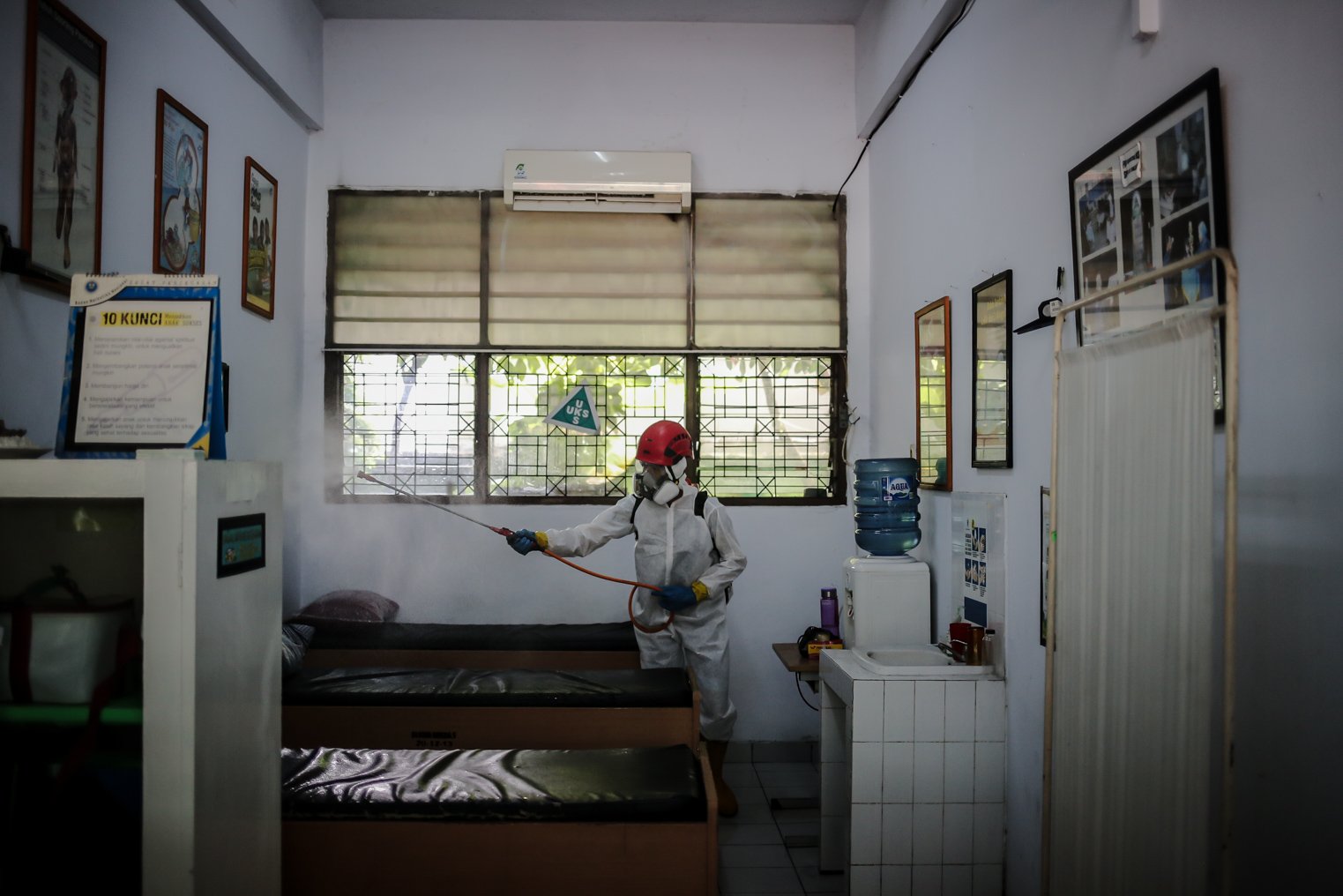 Petugas PMI menyemprotkan disinfektan di ruang UKS SMPN 97 Jakarta, Kamis (3/2/2022). Pemerintah DKI Jakarta telah mengeluarkan kebijakan untuk memberhentikan PTM di tengah melonjaknya kasus COVID-19 di DKI Jakarta. Sejumlah sekolah melakukan upaya antisipasi penyebaran COVID-19 dengan penyemprotan disinfektan, melakukan tes usap PCR peserta didik dan tenaga kependidikan juga menggelar Pembelajaran Jarak Jauh (PJJ).