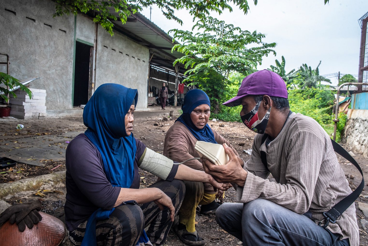 Aminah (kiri) dan Datri (tengah) memeriksakan tekanan darah kepada tukang tensi keliling di kawasan Belah Kapal, Cilincing, Jakarta Utara.