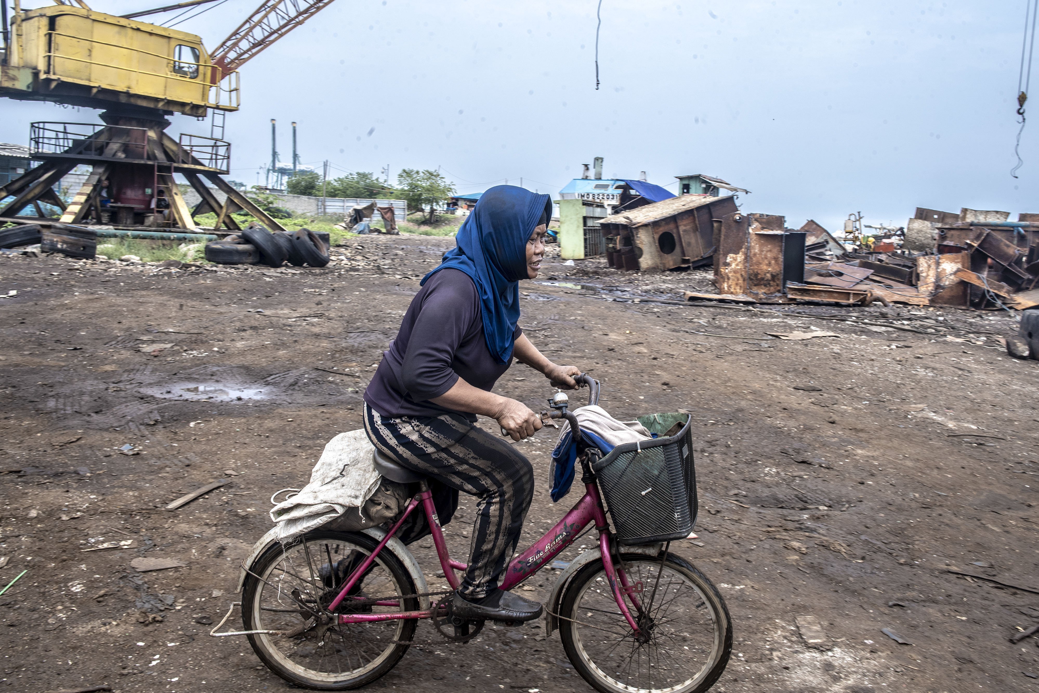 Aminah mengayuh sepedanya saat akan mulai bekerja di kawasan Belah Kapal, Cilincing, Jakarta Utara.