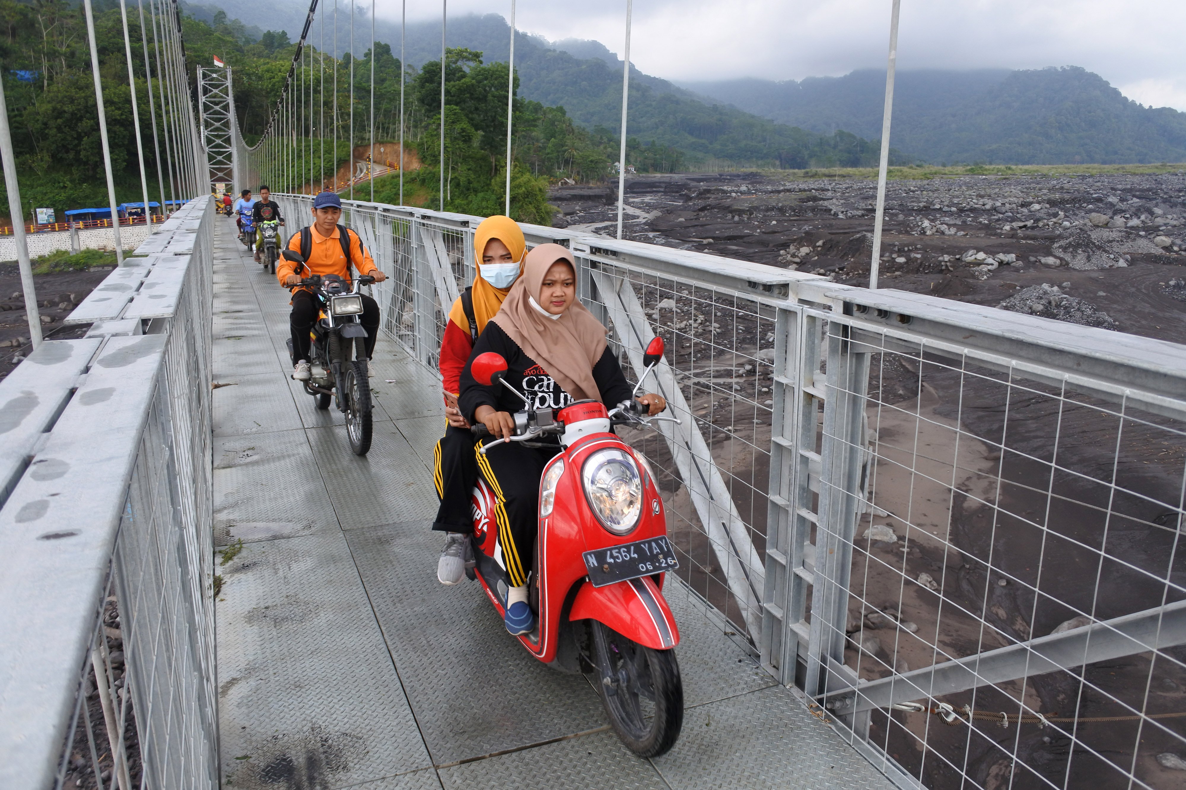 Guru SDN Jugosari 03 Eri Eliyawati, Lilik, dan Purnomo Candra Ronata menyebrangi jembatan gantung Sungai Regoyo di Desa Jugosari, Candipuro, Lumajang, Jawa Timur.