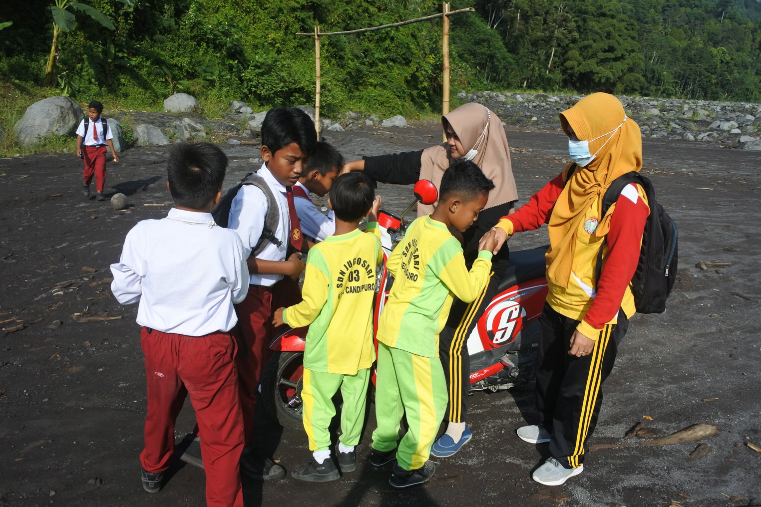 Guru SDN Jugosari 03 Eri Eliyawati, Lilik disambut sejumlah murid di pinggir Sungai Regoyo di Desa Jugosari, Candipuro, Lumajang, Jawa Timur.