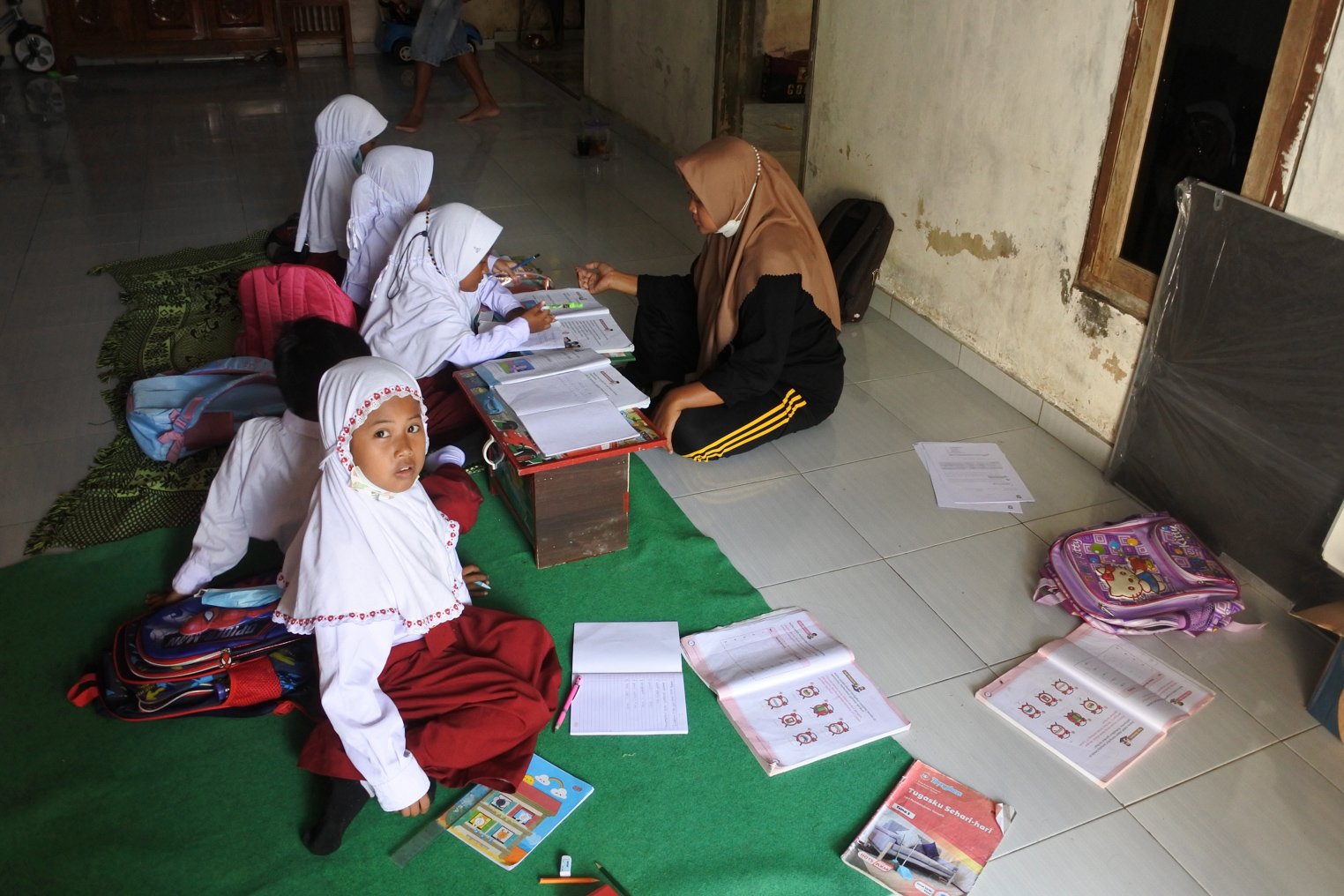 Guru SDN Jugosari 03 Eri Eliyawati mengajar sejumlah muridnya di rumah warga di Dusun Sumerlangsep, Desa Jugosari, Candipuro, Lumajang, Jawa Timur.