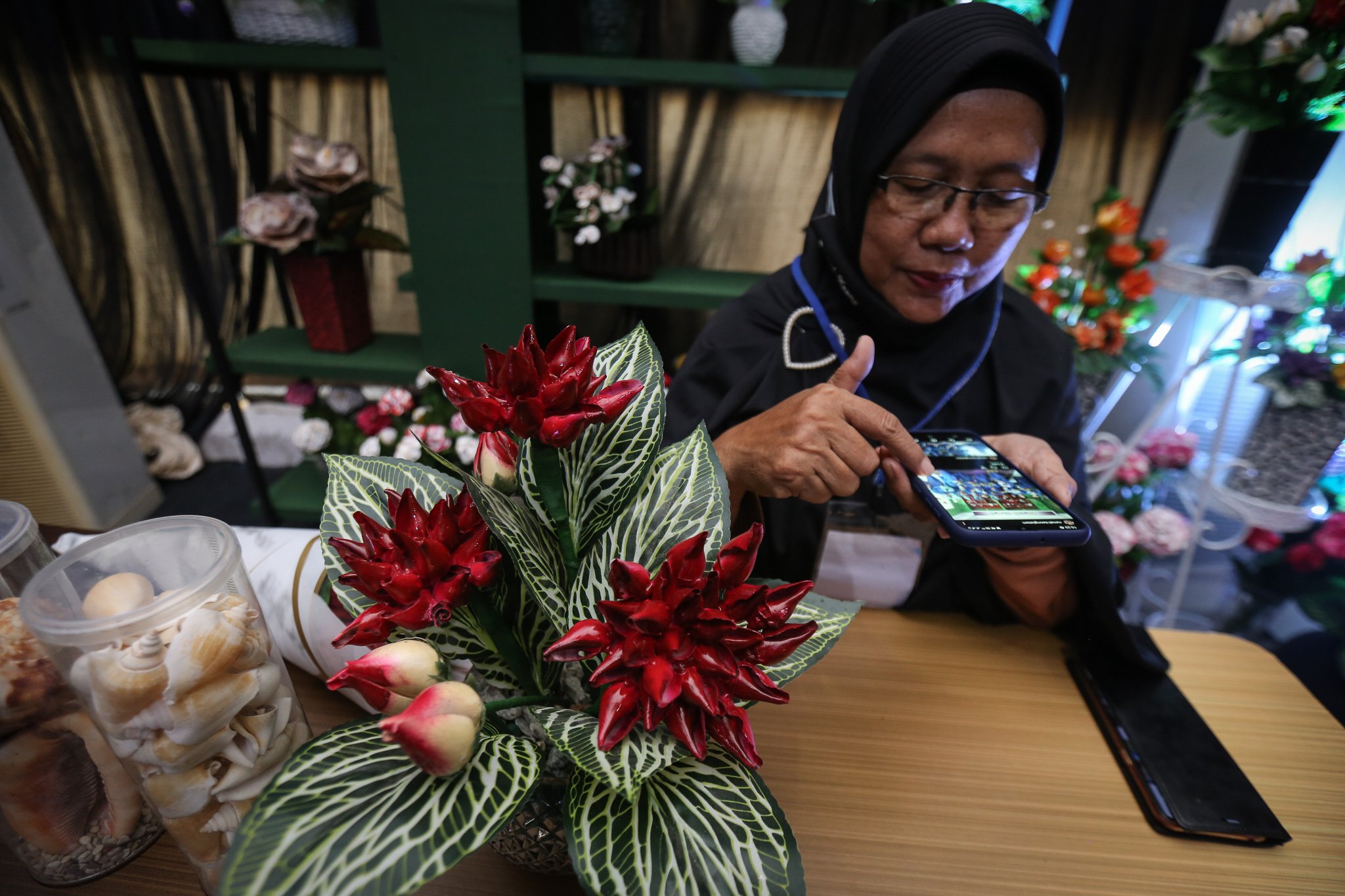 Suyanti melihat katalog produk cangkang gonggong miliknya pada paltform digital di UMKM Rumah Keong, Batam, Kepulauan Riau.