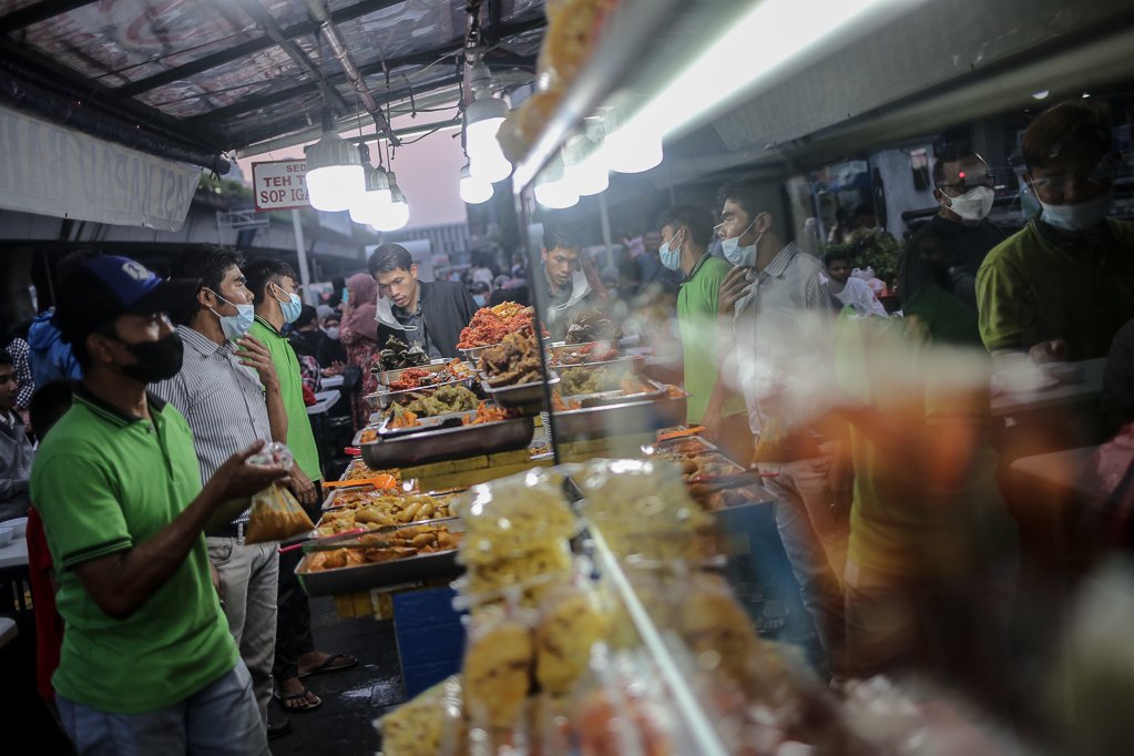 Sejumlah warga mengantre saat membeli menu berbuka puasa di Sentra kuliner Nasi Kapau di Jalan Kramat Raya, Senen, Jakarta Pusat, Selasa (12/4/2021). Menjelang berbuka puasa sentra kuliner yang menyajikan makanan khas sumatra barat ini selalu ramai dikunjungi pembeli.