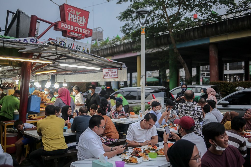 Sejumlah warga duduk sambil menunggu berbuka puasa di Sentra kuliner Nasi Kapau di Jalan Kramat Raya, Senen, Jakarta Pusat, Selasa (12/4/2021). Menjelang berbuka puasa sentra kuliner yang menyajikan makanan khas sumatra barat ini selalu ramai dikunjungi pembeli.
