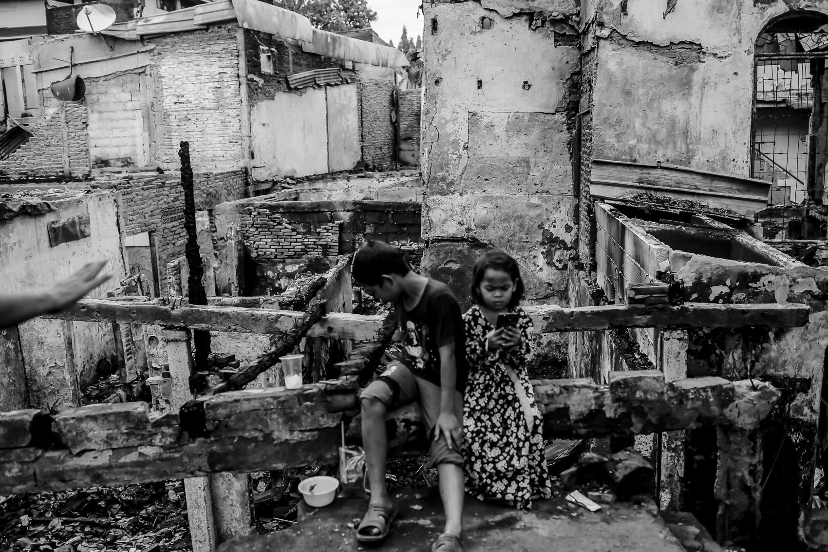 Dua orang anak bermain di depan rumahnya yang terbakar, Pasar Gembrong, Jakarta, Rabu (4/5/2022). Luas area yang terbakar mencapai 1.200 meter persegi. Sebanyak 26 unit mobil pemadam beserta 130 personel diterjunkan ke lokasi untuk memadamkan api saat kejadian.