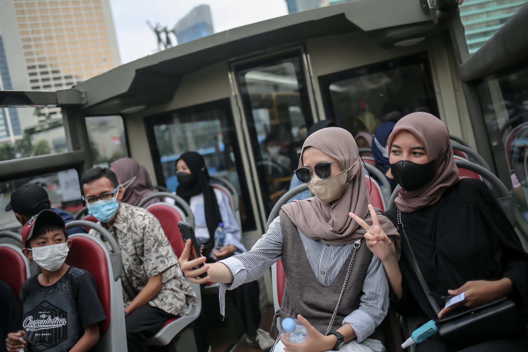 Warga melakukan swa-foto saat menikmati suasana kota dari bus wisata terbuka gratis di Jakarta, Selasa, (10/5/2022). PT Transportasi Jakarta (Transjakarta) memfasilitasi layanan bus wisata gratis selama libur lebaran 2022.