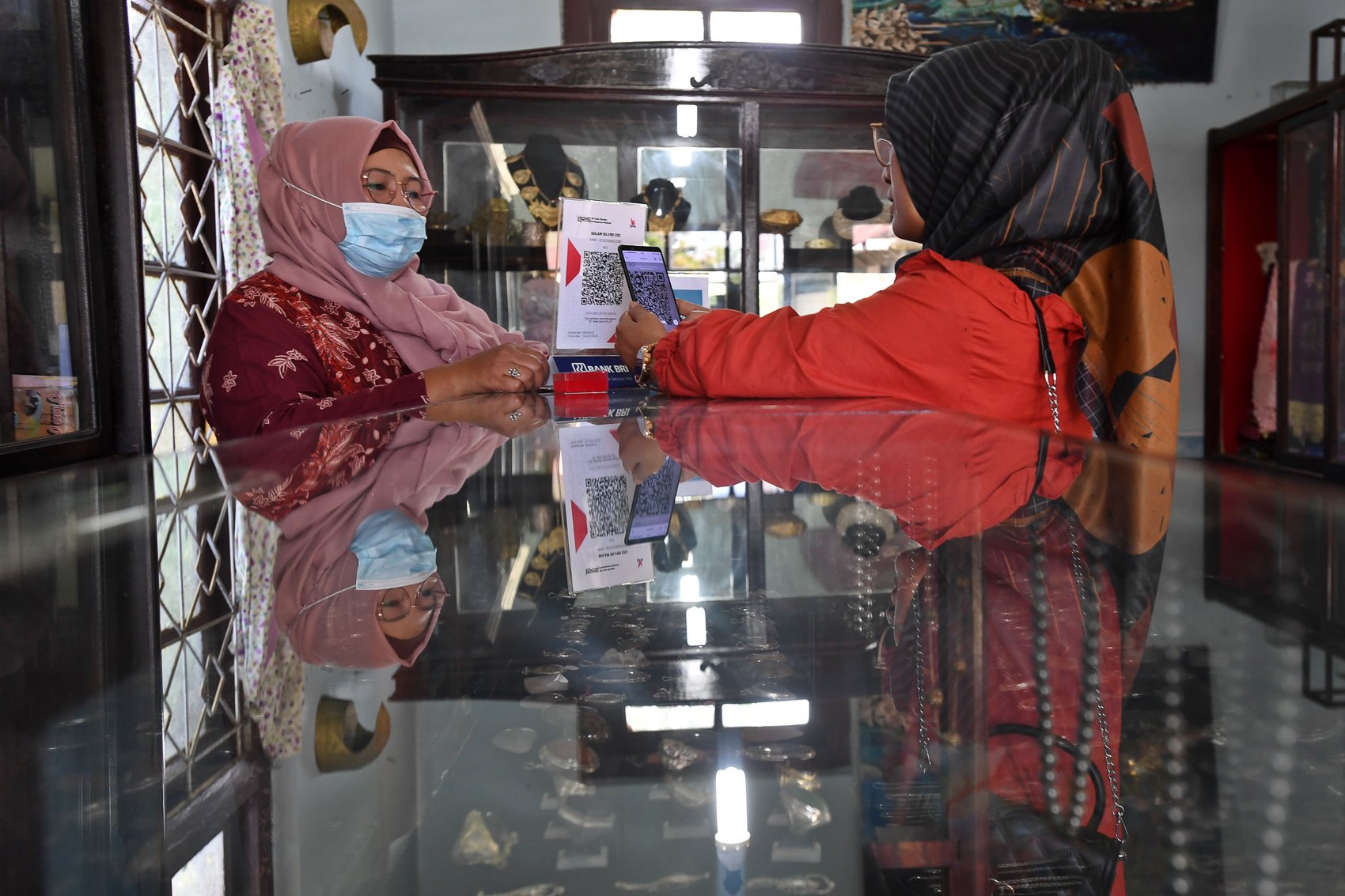 Fitri Haryanti melayani pembeli saat bertransaksi dengan pembayaran non tunai di galeri Silver Cici, sentra kerajinan perak Nagari Koto Gadang, Kabupaten Agam, Sumatera Barat.