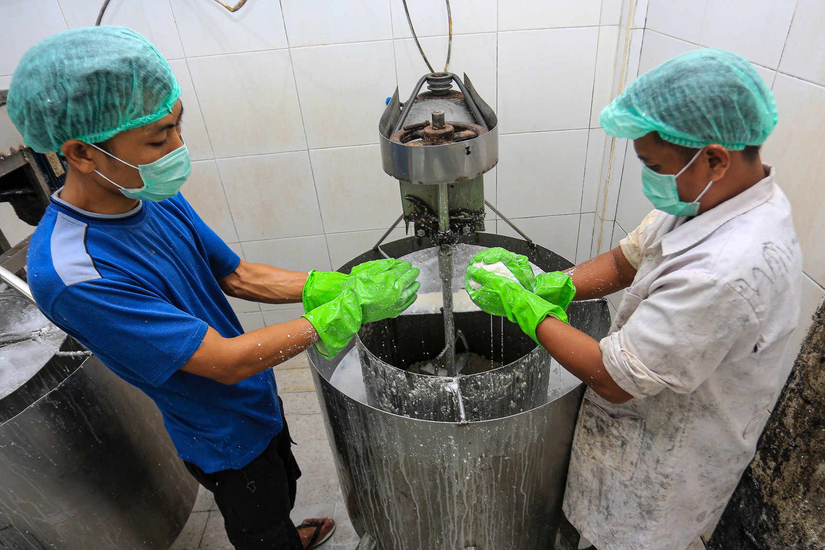 Pekerja menggunakan mesin produksi melakukan pembuatan minyak kelapa murni