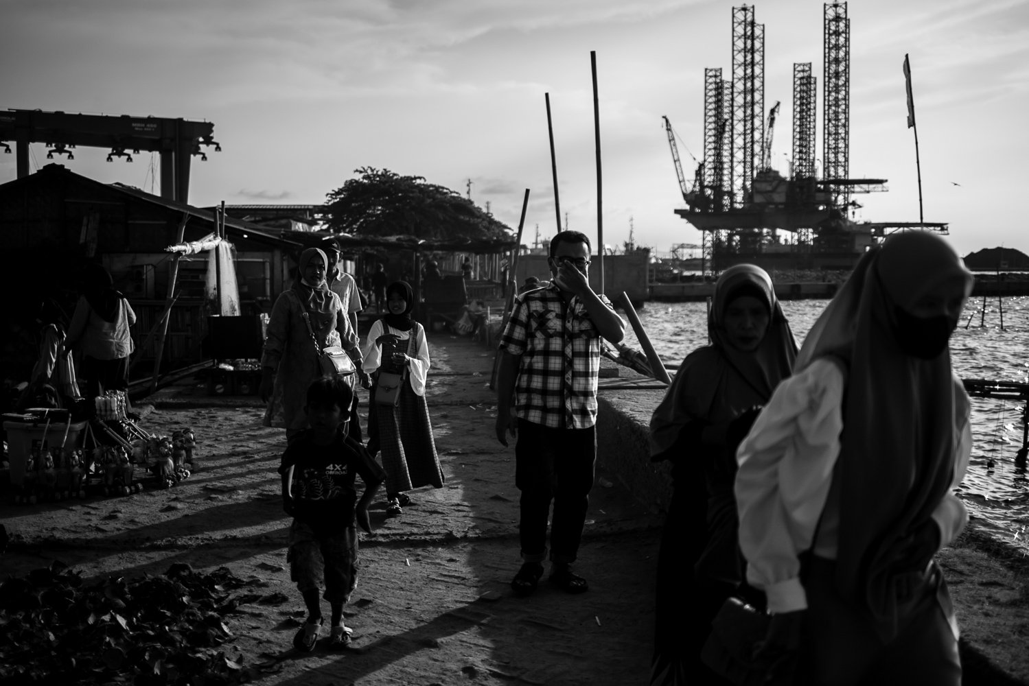 Sejumlah warga melintas di wilayah Pantai Marunda yang berhadapan langsung dengan aktivitas bongkar muat batubara oleh PT Karya Citra Nusantara (KCN) di Pelabuhan Marunda.
