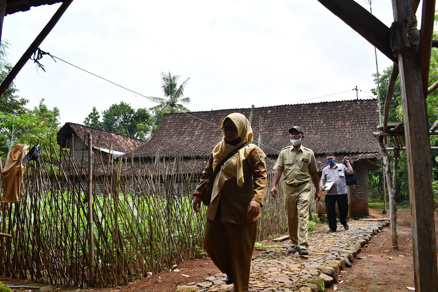 Petugas Dinas Kependudukan dan Pencatatan Sipil bersama perangkat desa berjalan menuju rumah warga penyandang disabilitas untuk melakukan perekaman e-KTP di Desa Morang, Kecamatan Kare, Kabupaten Madiun, Jawa Timur.