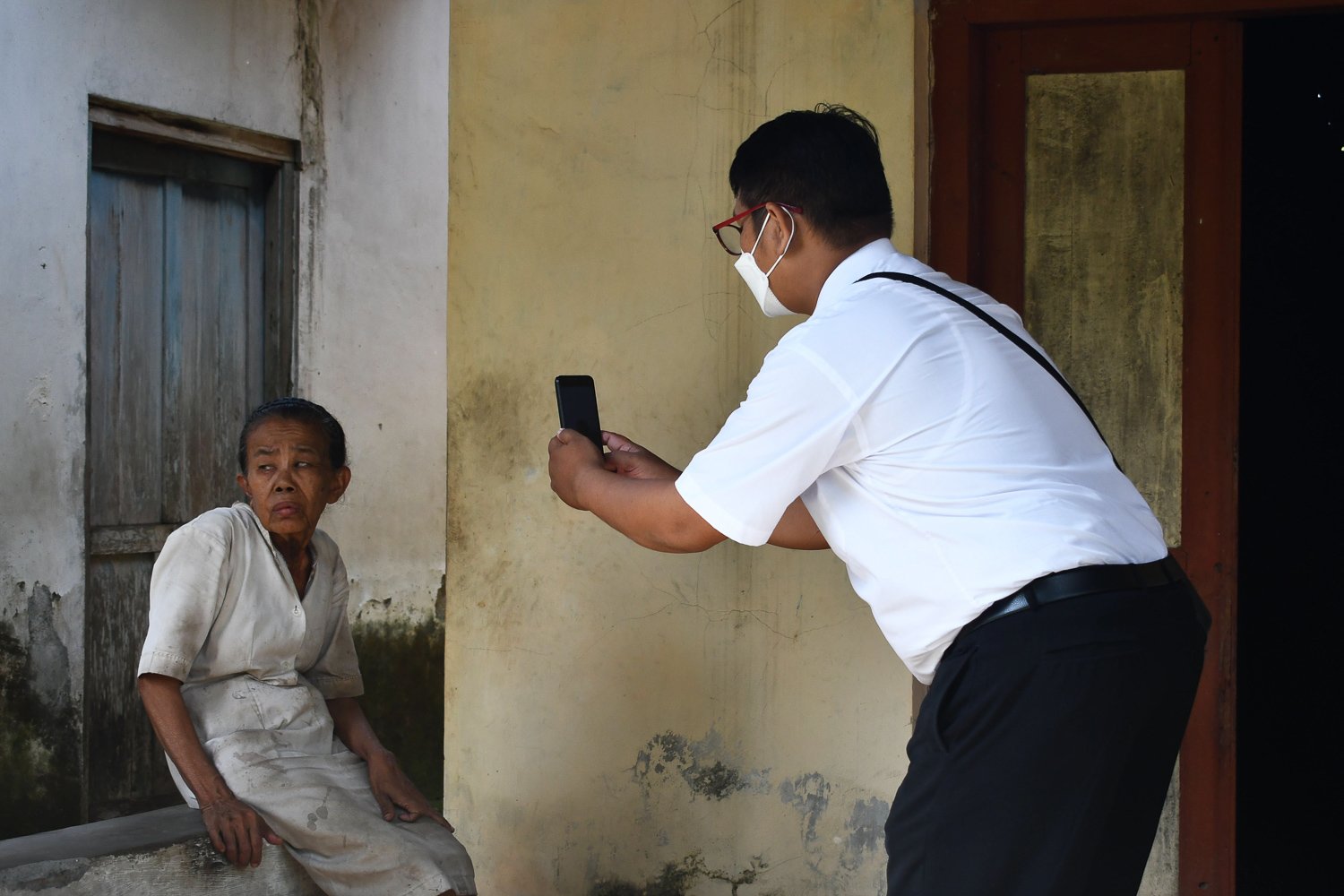 Petugas Dinas Kependudukan dan Pencatatan Sipil melakukan pemotretan menggunakan smartphone perekaman e-KTP bagi warga penyandang disabilitas di Kelurahan Nglames, Kabupaten Madiun, Jawa Timur.
