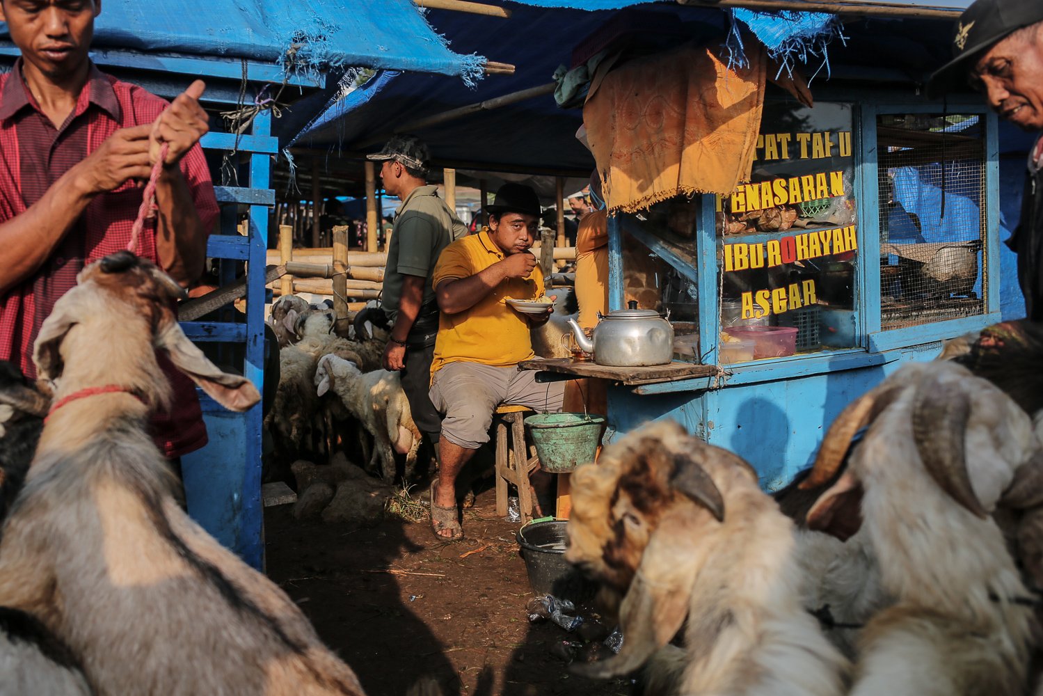 Sejumlah pedagang menyantap bubur ayam saat menjajakan hewan untuk kurban di Pasar Hewan Jonggol, Kabupaten Bogor, Jawa Barat, Kamis (7/7). Menjelang hari raya Iduladha pengelola Pasar Hewan Jonggol mengaku penjualan hewan kurban mengalami penurunan drastis hingga 80 persen dibanding dengan tahun lalu, hal itu diakibatkan dampak dari penyakit mulut dan kuku (PMK).