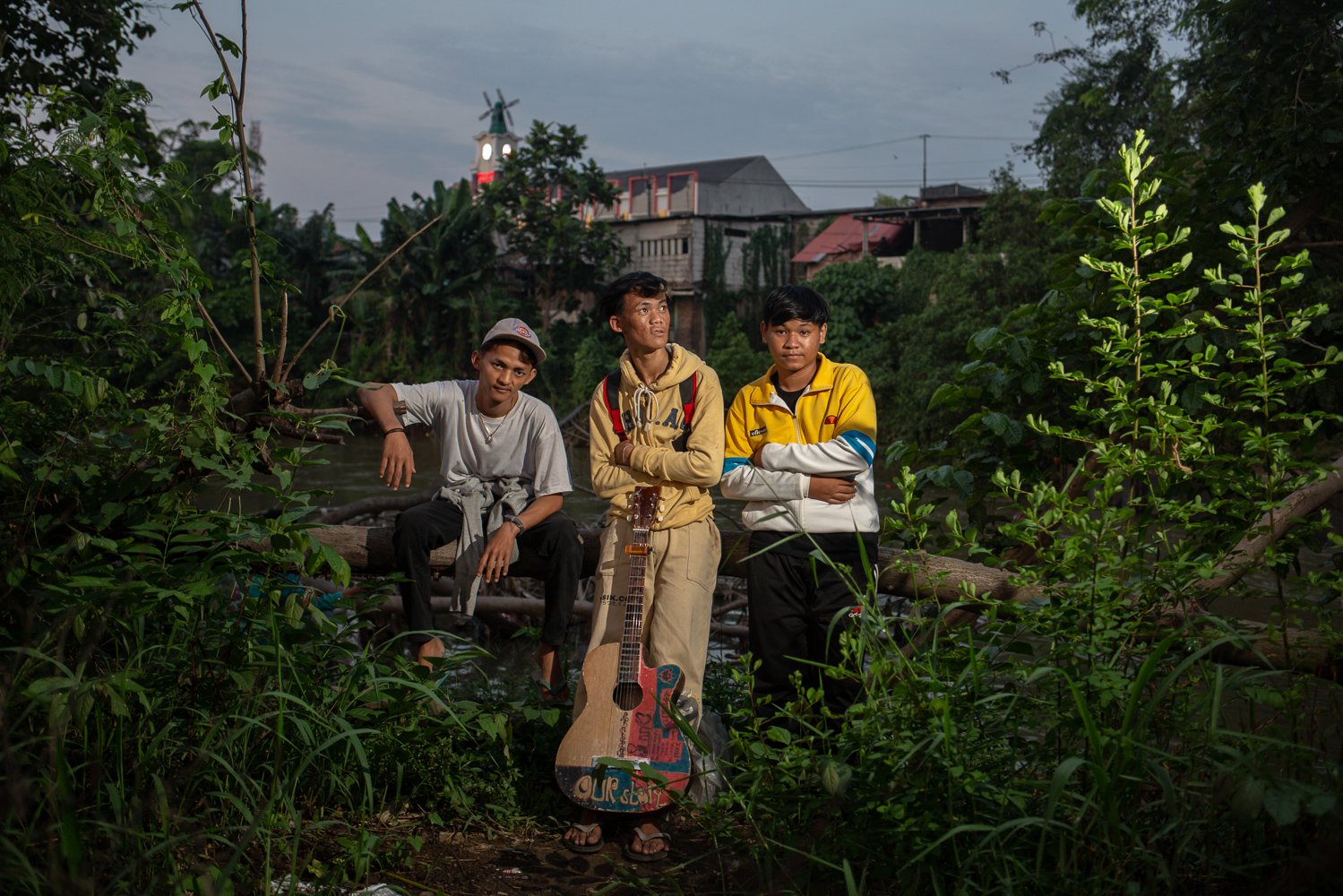 Damar (kiri) Tristan Ecky (tengah) dan Ilham Saputra (kanan) berpose dengan latar belakang lanskap pemukiman mereka tinggal di Cikarang Barat, Kabupaten Bekasi, Jawa Barat, Senin (18/7).
