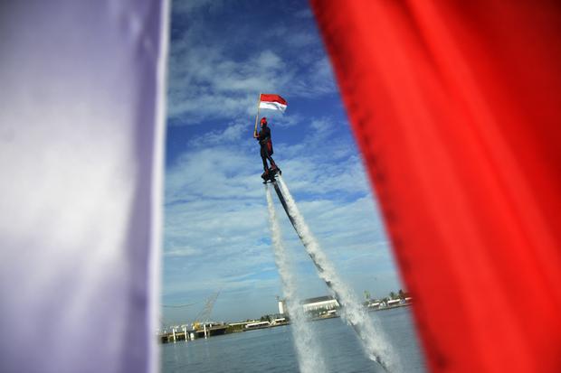 Warga melakukan atraksi flyboar sambil membawa bendera Merah Putih di Pantai Losari, Makassar, Sulawesi Selatan, Rabu (17/8/2022). Atraksi tersebut dalam rangka memeriahkan peringatan HUT ke-77 Kemerdekaan Republik Indonesa.