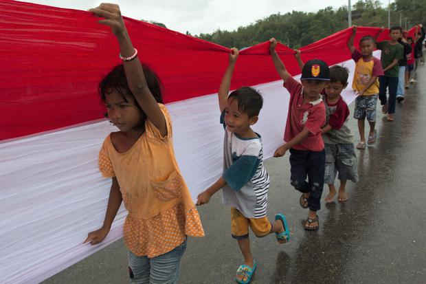 Sejumlah anak membantu memegang bendera Merah Putih saat pembentangan bendera di Jembatan Teluk Kendari, Kendari, Sulawesi Tenggara, Rabu (17/8/2022). Mahasiswa Universitas Muhammadiyah Kendari (UMK) bersama pelajar dan warga membentangkan bendera sepanjang 770 meter di atas Jembatan Teluk Kendari untuk memperingati HUT ke-77 Kemerdekaan RI.