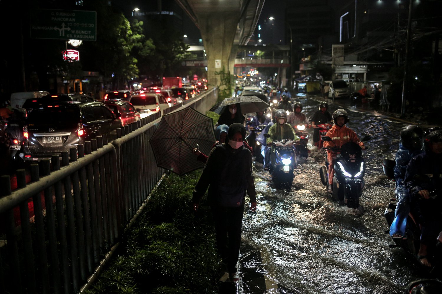 Pekerja berjalan diatas separator untuk menhindari genangan air yang merendam Jalan Kapten Tendean, Jakarta, Selasa (4/10). Hujan lebat yang mengguyur DKI Jakarta menyebabkan sejumlah wilayah di Ibu Kota terendam banjir.