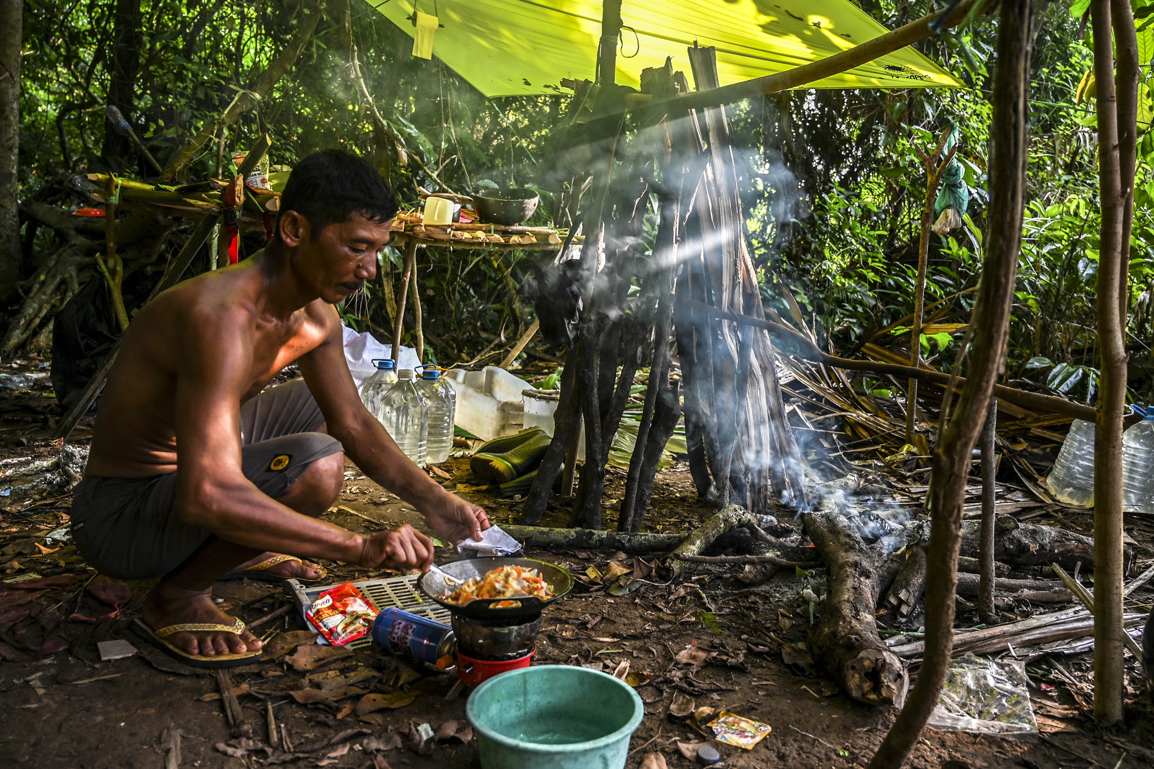 Seorang porter yang bertugas sebagai juru masak mengolah bahan makanan saat mendampingi tamu yang hendak masuk ke dalam kawasan Taman Nasional Ujung Kulon di Pandeglang, Banten.