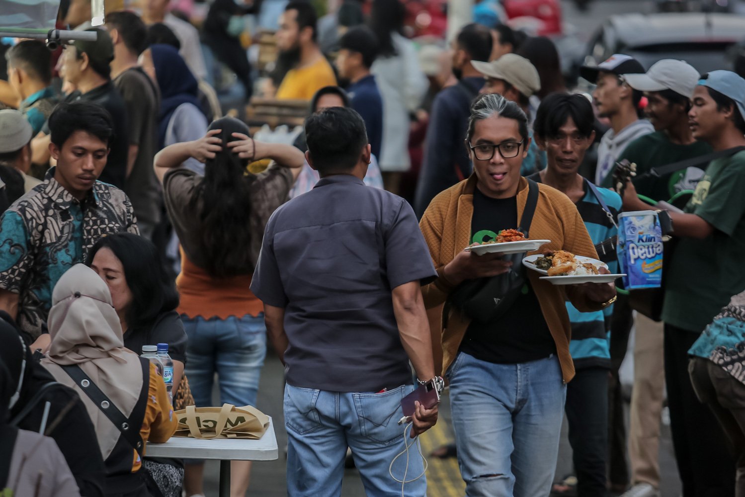 Pengunjung berjalan membawa makanan di Sentra kuliner Nasi Kapau, Jalan Kramat Raya, Senen, Jakarta Pusat, Jumat (24/3). Menjelang berbuka puasa sentra kuliner yang menyajikan Nasi Kapau dan berbagai makanan khas sumatra barat ini ramai dikunjungi pembeli.