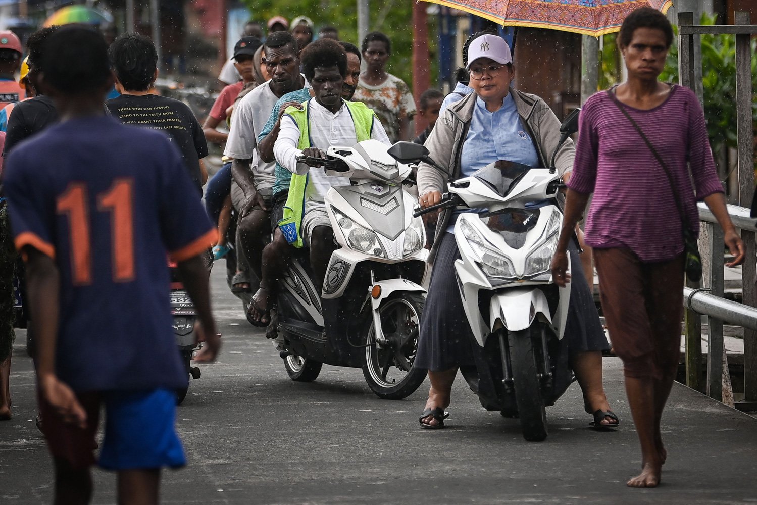 Sejumlah warga mengendarai sepeda motor listrik di Jalan Yos Sudarso, Agats, Kabupaten Asmat, Papua Selatan.