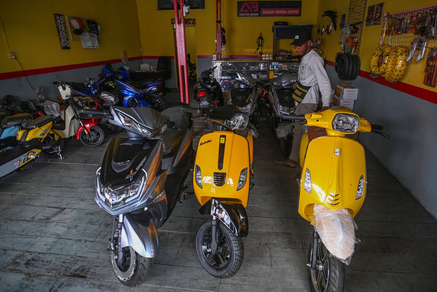 Warga mengamati sepeda motor listrik yang dijual di Agats, Kabupaten Asmat, Papua Selatan.